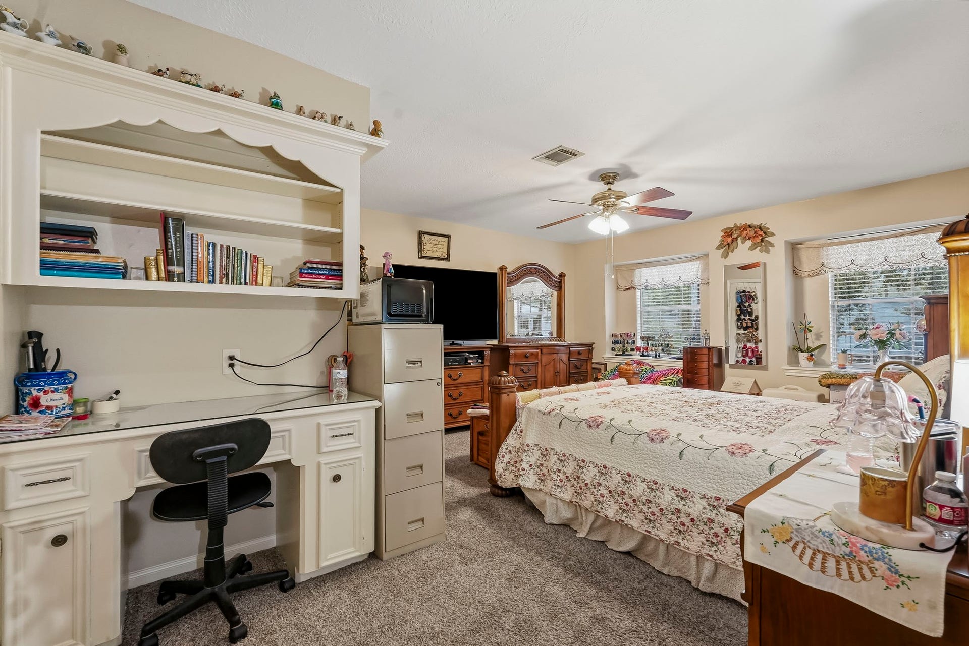 3610 Valley Haven Drive, Houston, TX 77339 Spacious secondary bedroom with cozy carpet features a built-in desk, ample shelving, and large windows for natural light, complemented by a ceiling fan.