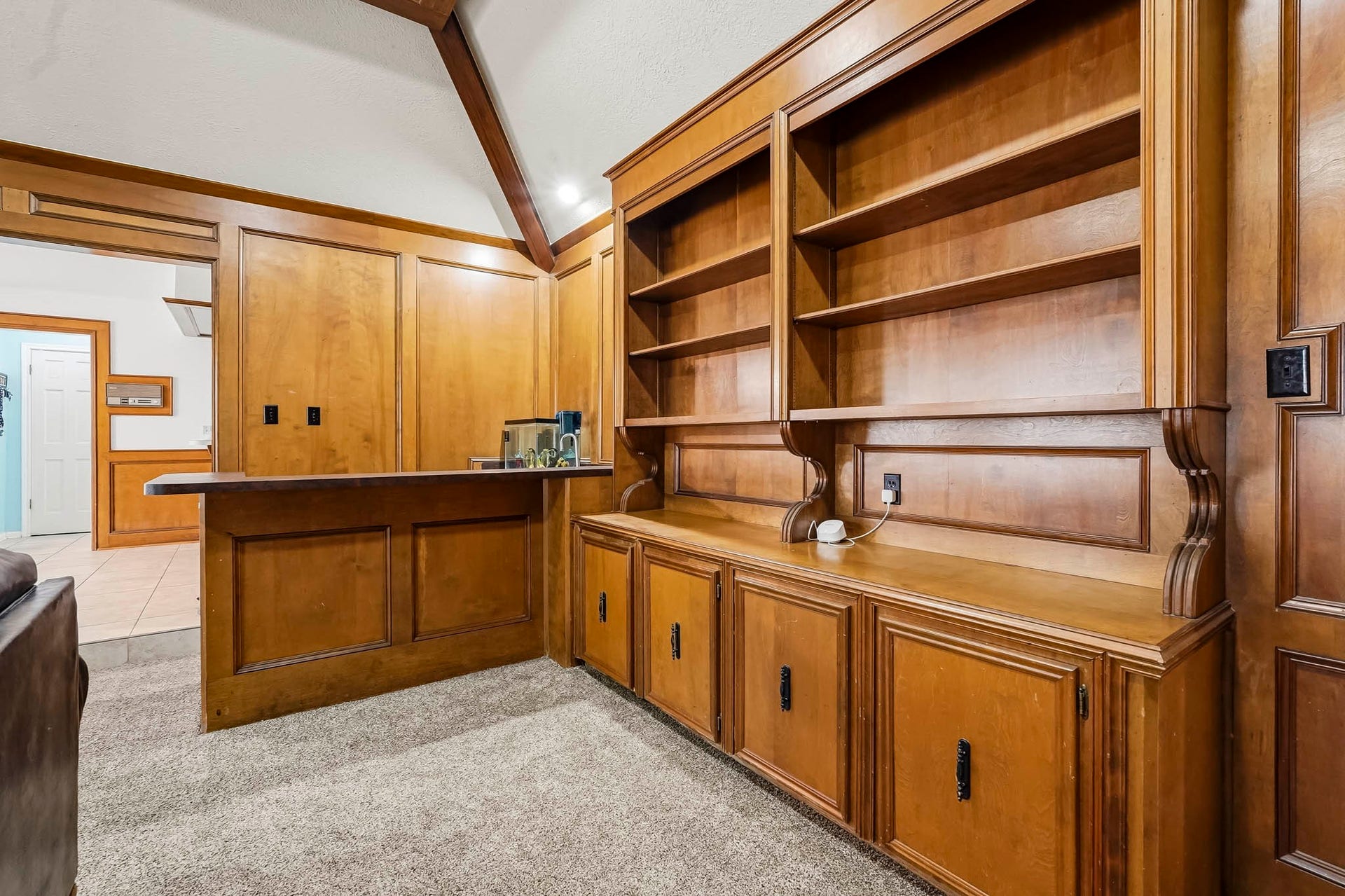 3610 Valley Haven Drive, Houston, TX 77339 Elegant wooden built-in bookshelves offer ample storage and display space, seamlessly blending with the rich wood paneling and cozy carpeted flooring, creating a warm, inviting atmosphere.