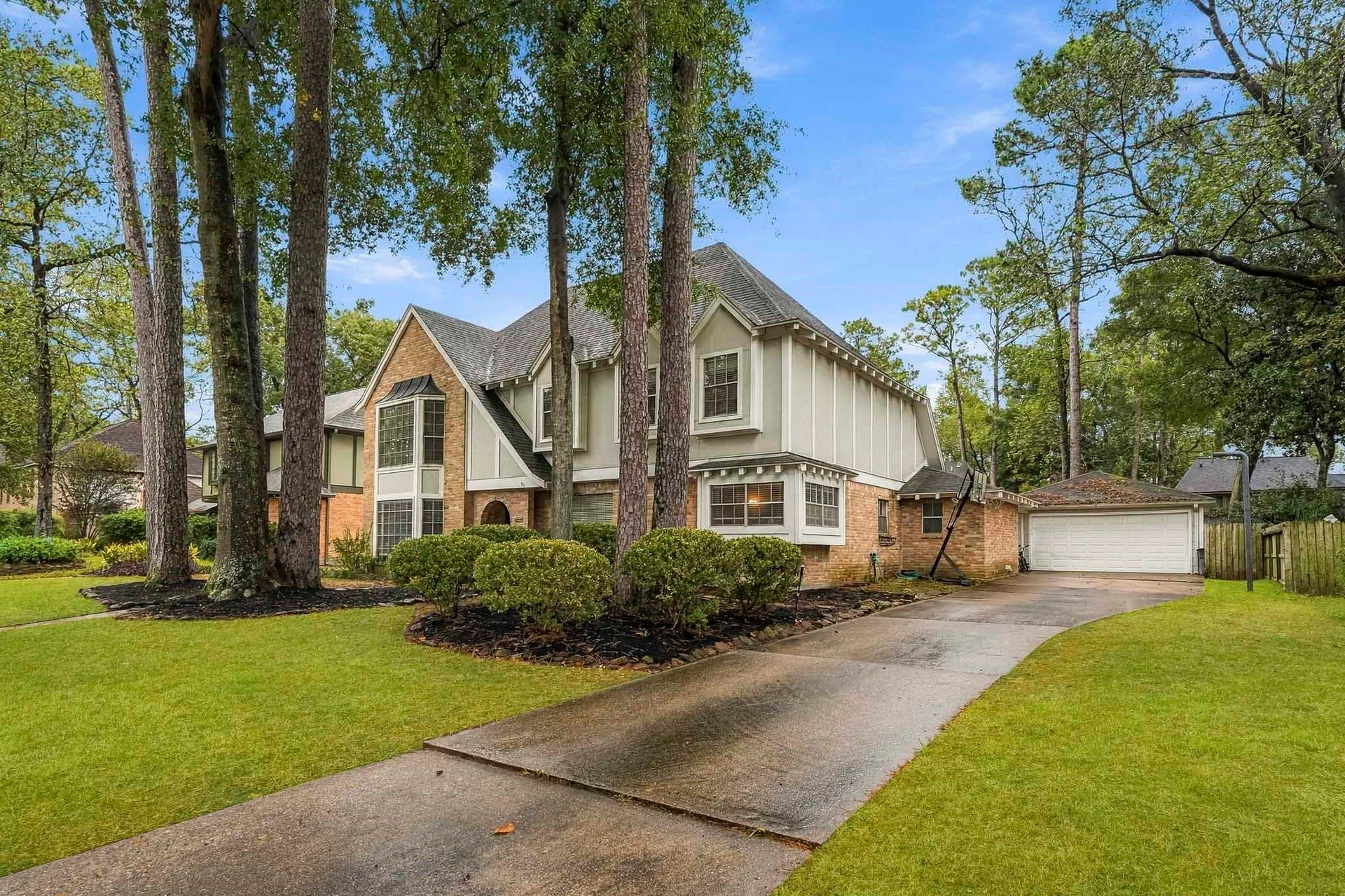 3610 Valley Haven Drive, Houston, TX 77339 Charming two-story home nestled among mature trees, featuring a classic brick and siding exterior with a spacious driveway leading to a detached garage.