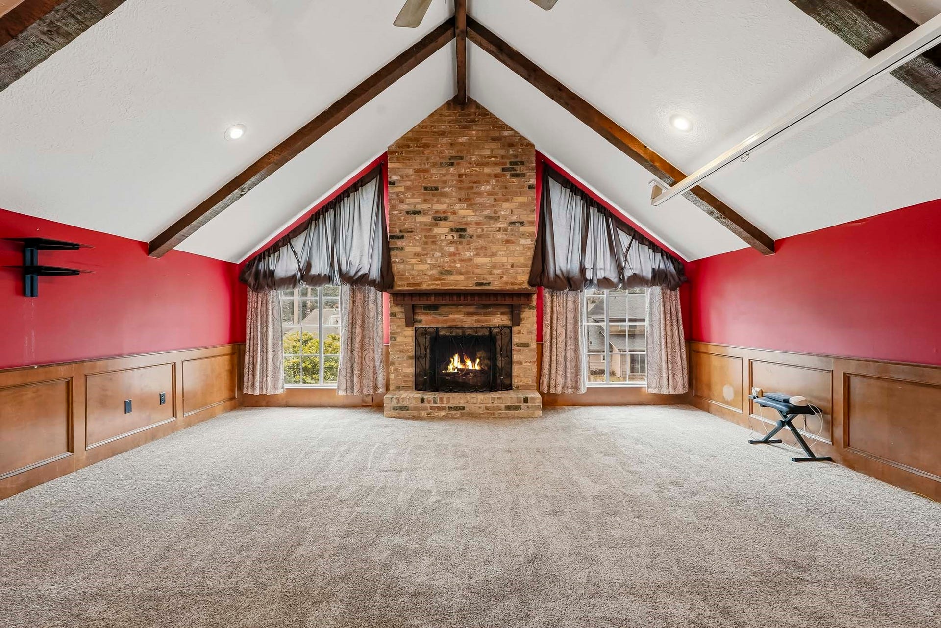 3610 Valley Haven Drive, Houston, TX 77339 Spacious game room featuring a dramatic vaulted ceiling with exposed beams, a cozy brick fireplace, and walls complemented by elegant wood paneling.