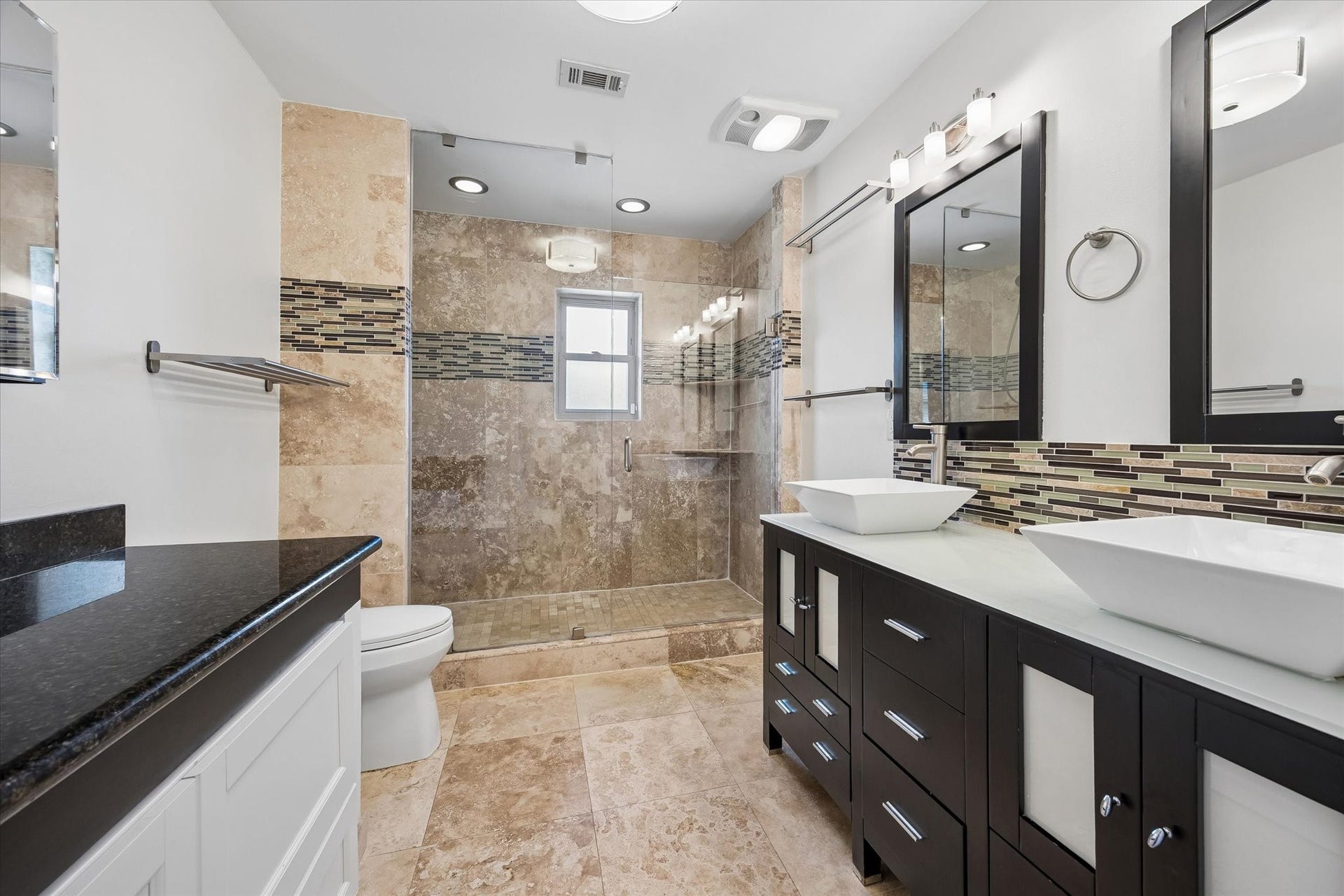 10831 Olympia Drive, Houston, TX 77042 The beautiful primary bath features a seamless glass shower with built-in shelving, double sinks, and an additional vanity with clever integrated storage.