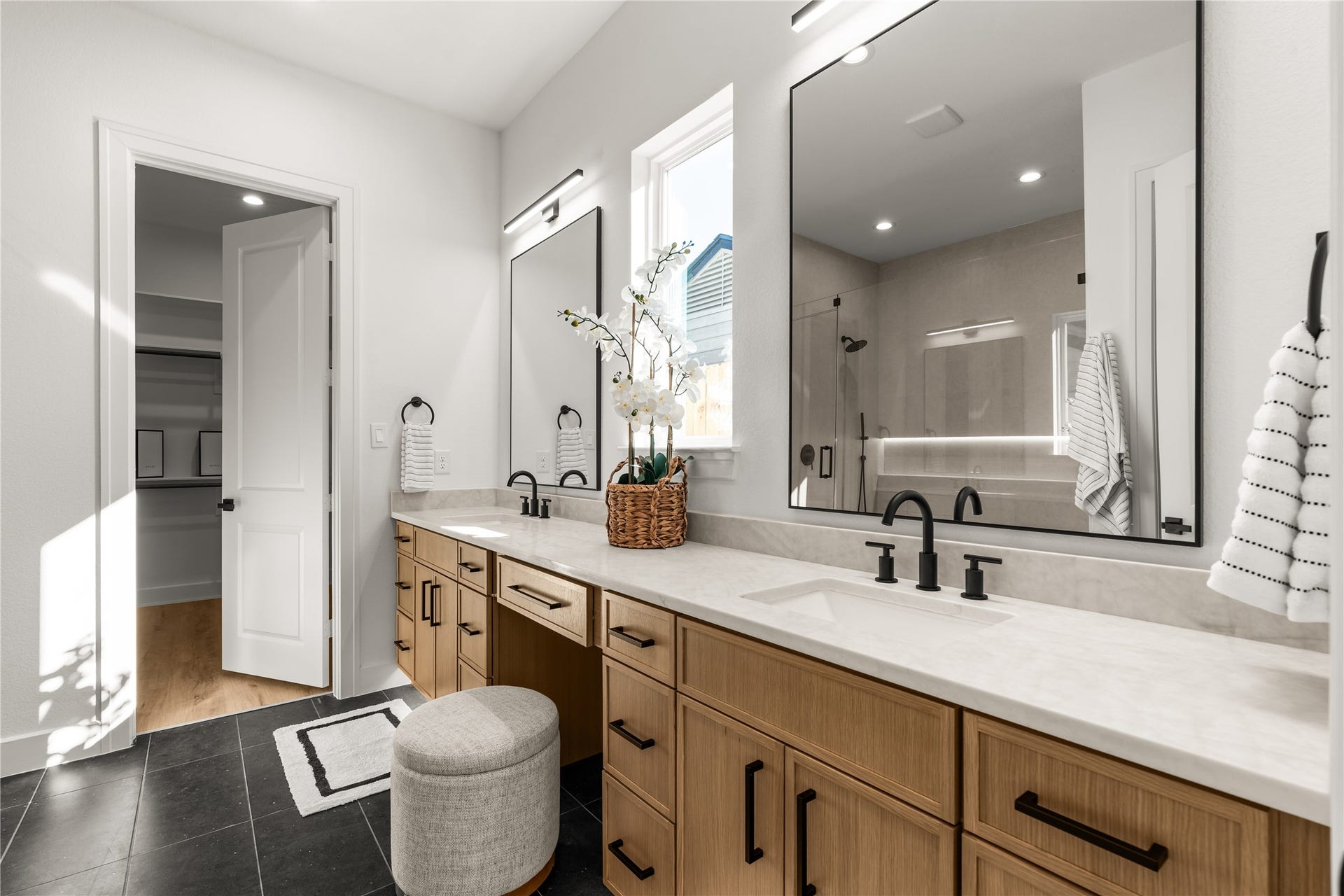 6714 Tierwester Street, Houston, TX 77021 The primary ensuite showcases an expansive dual-sink vanity with warm wood-toned cabinetry, light stone-look countertops, and matte black fixtures.