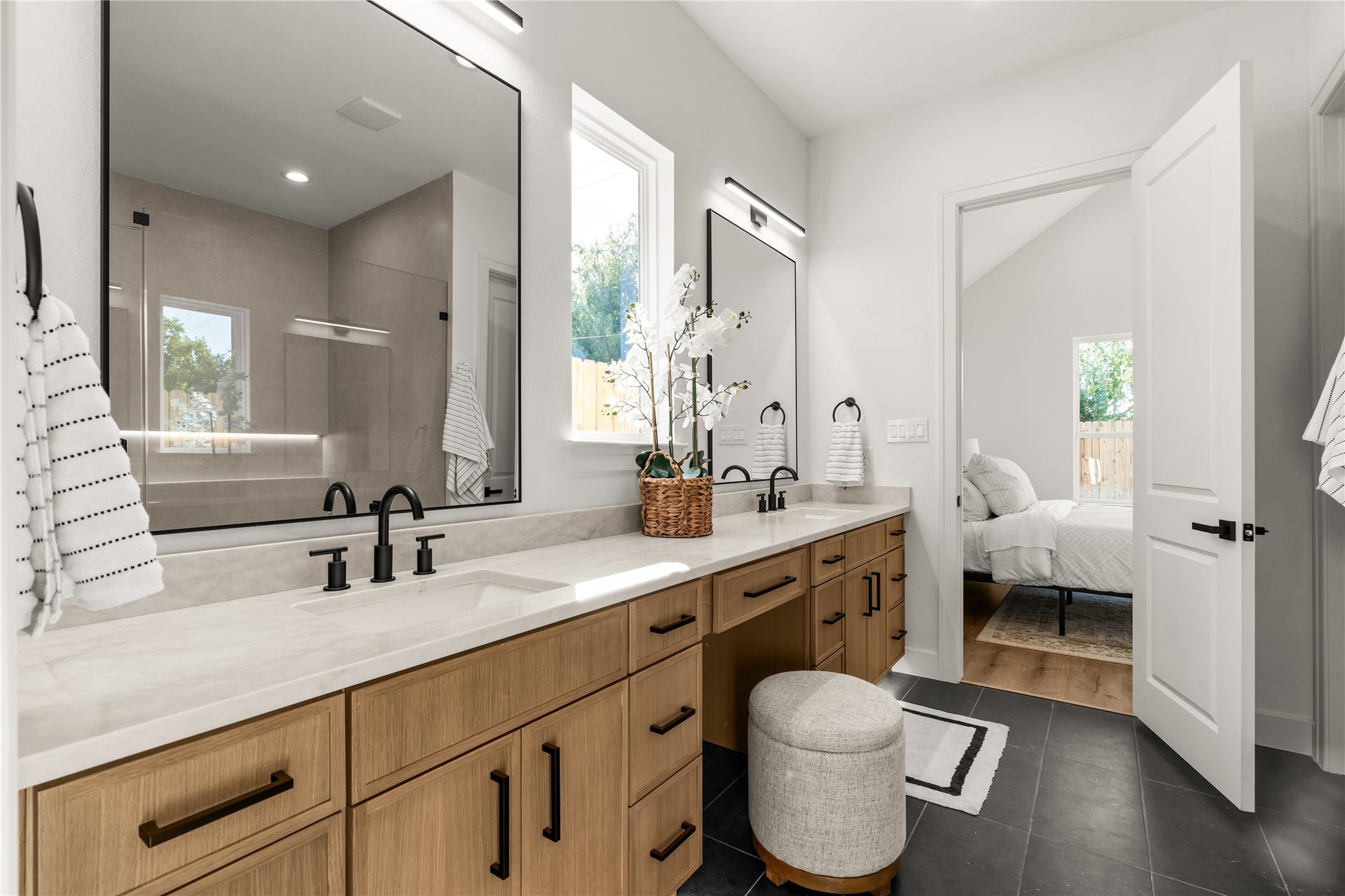 6714 Tierwester Street, Houston, TX 77021 Spanning the length of the primary ensuite, the dual-sink vanity showcases warm cabinetry accented by matte black hardware and sleek surfaces.