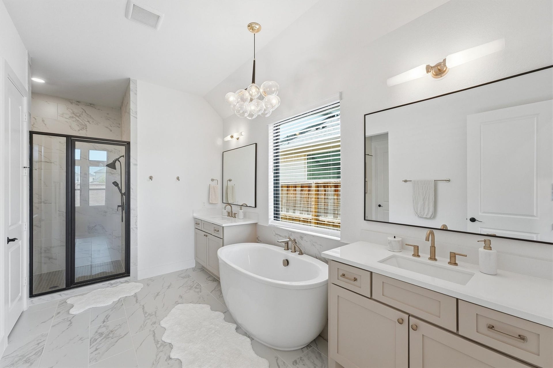 20222 Palomar Pointe Drive, Cypress, TX 77433 Experience the epitome of luxury in this spa-inspired primary bathroom, featuring a freestanding soaking tub, oversized walk-in shower, and dual vanities, all adorned with elegant marble-look tile and accented by sophisticated gold fixtures and designer lighting.