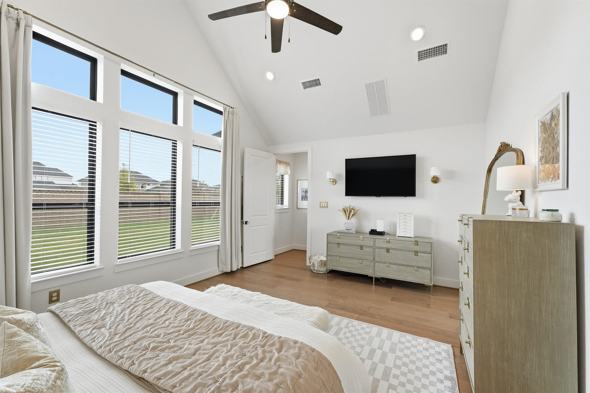 20222 Palomar Pointe Drive, Cypress, TX 77433 A serene primary bedroom retreat with soaring ceilings and modern finishes, bathed in natural light from oversized windows offering beautiful backyard views, creates a bright and relaxing atmosphere.