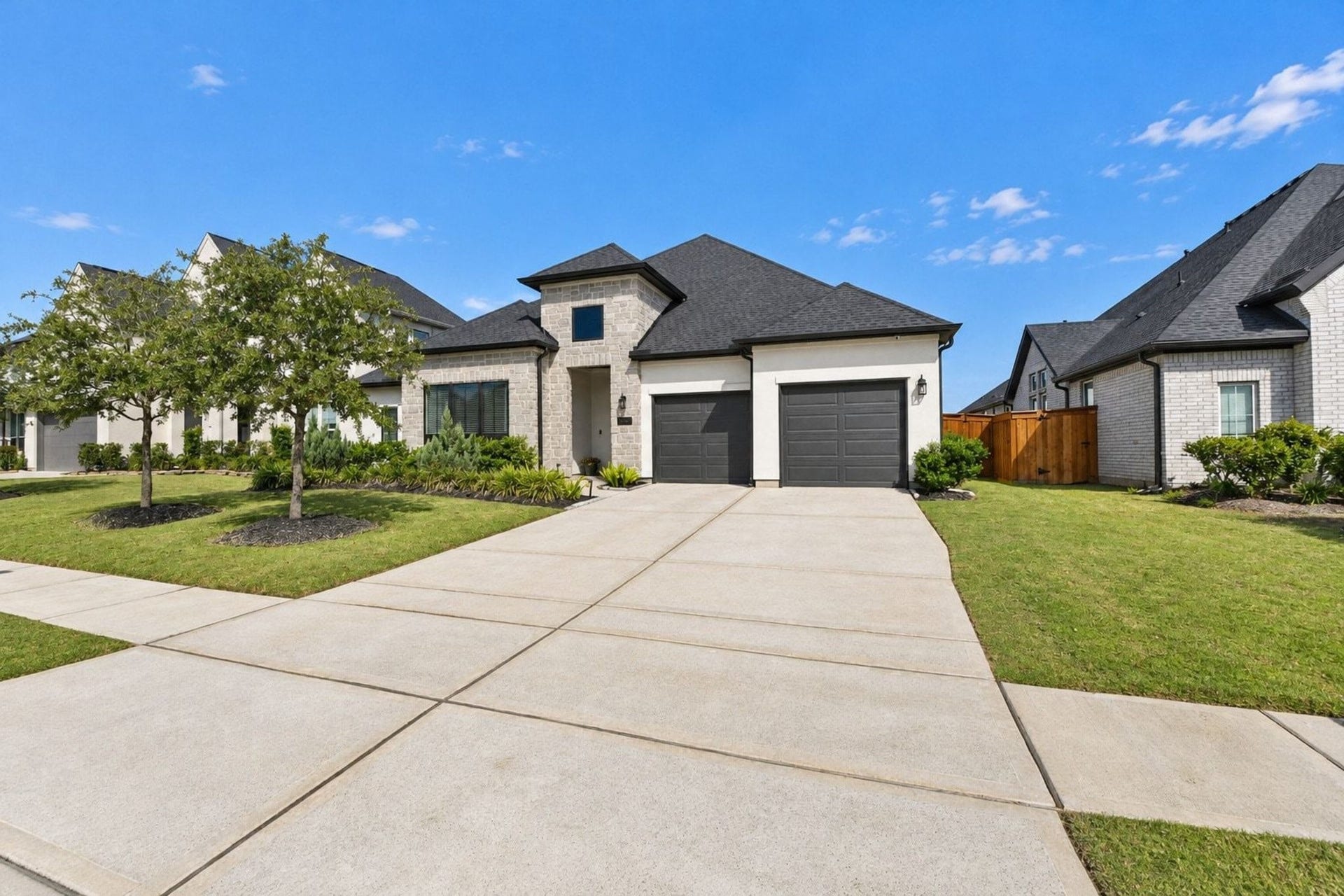 20222 Palomar Pointe Drive, Cypress, TX 77433 Modern single-story home with a sleek black roof, three-car tandem garage, and well-manicured lawn, offering great curb appeal.