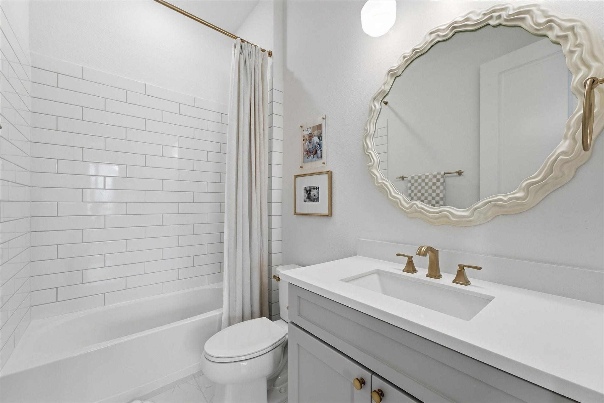 20222 Palomar Pointe Drive, Cypress, TX 77433 A stylish secondary bathroom featuring classic white subway tile, a sleek vanity, and warm gold fixtures. The statement mirror adds a fun designer touch while keeping the space bright, fresh, and modern.