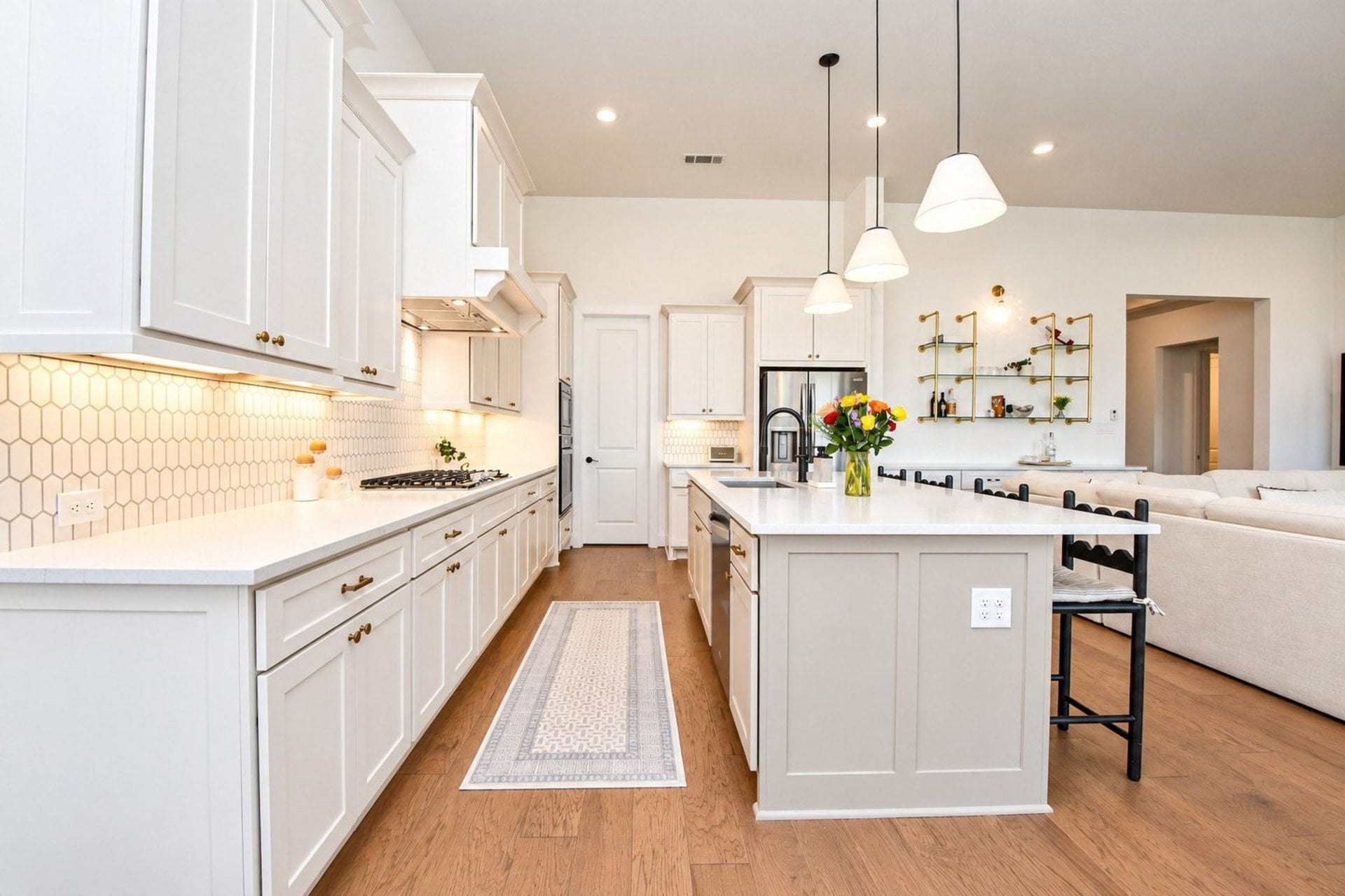 20222 Palomar Pointe Drive, Cypress, TX 77433 Spacious and modern kitchen featuring sleek white cabinetry, a large central island with pendant lighting, and elegant hardwood floors. The open design seamlessly connects to the living area, ideal for entertaining.