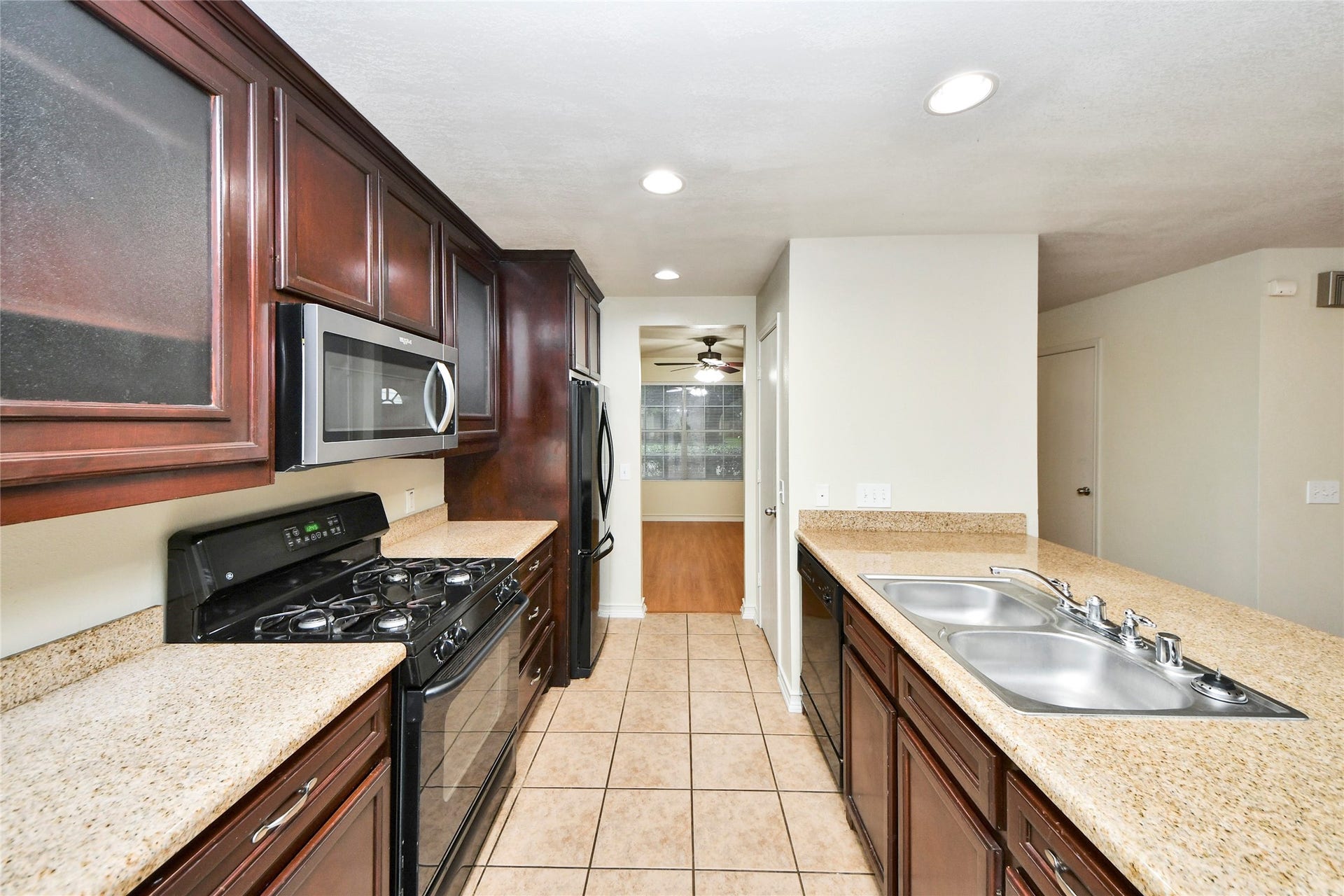 Modern kitchen with dark wood cabinetry, granite countertops, and stainless steel appliances, offering ample space and functionality.