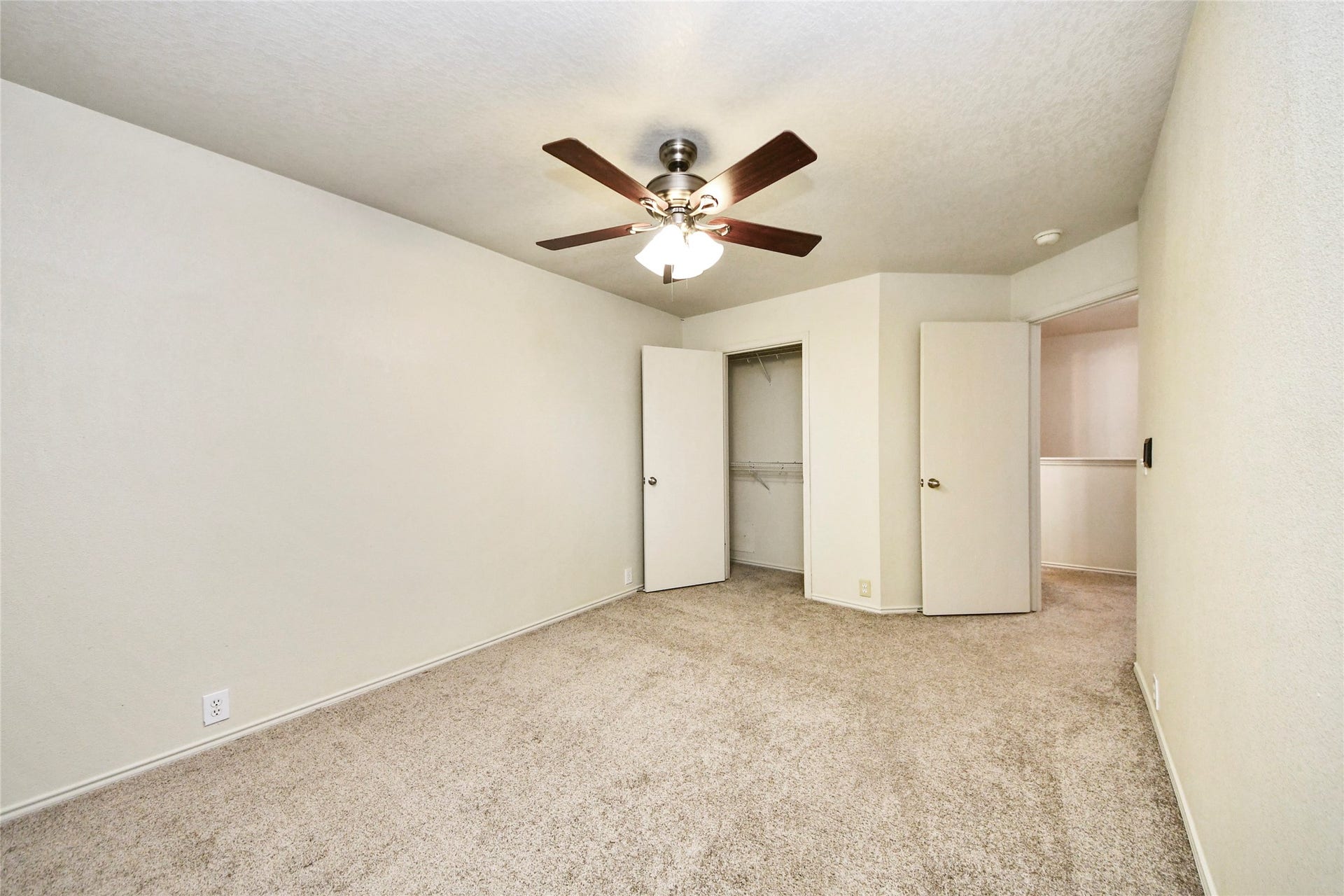 The third bedroom offers a spacious, carpeted retreat with a ceiling fan and ample closet space, perfect for relaxation or a guest room.