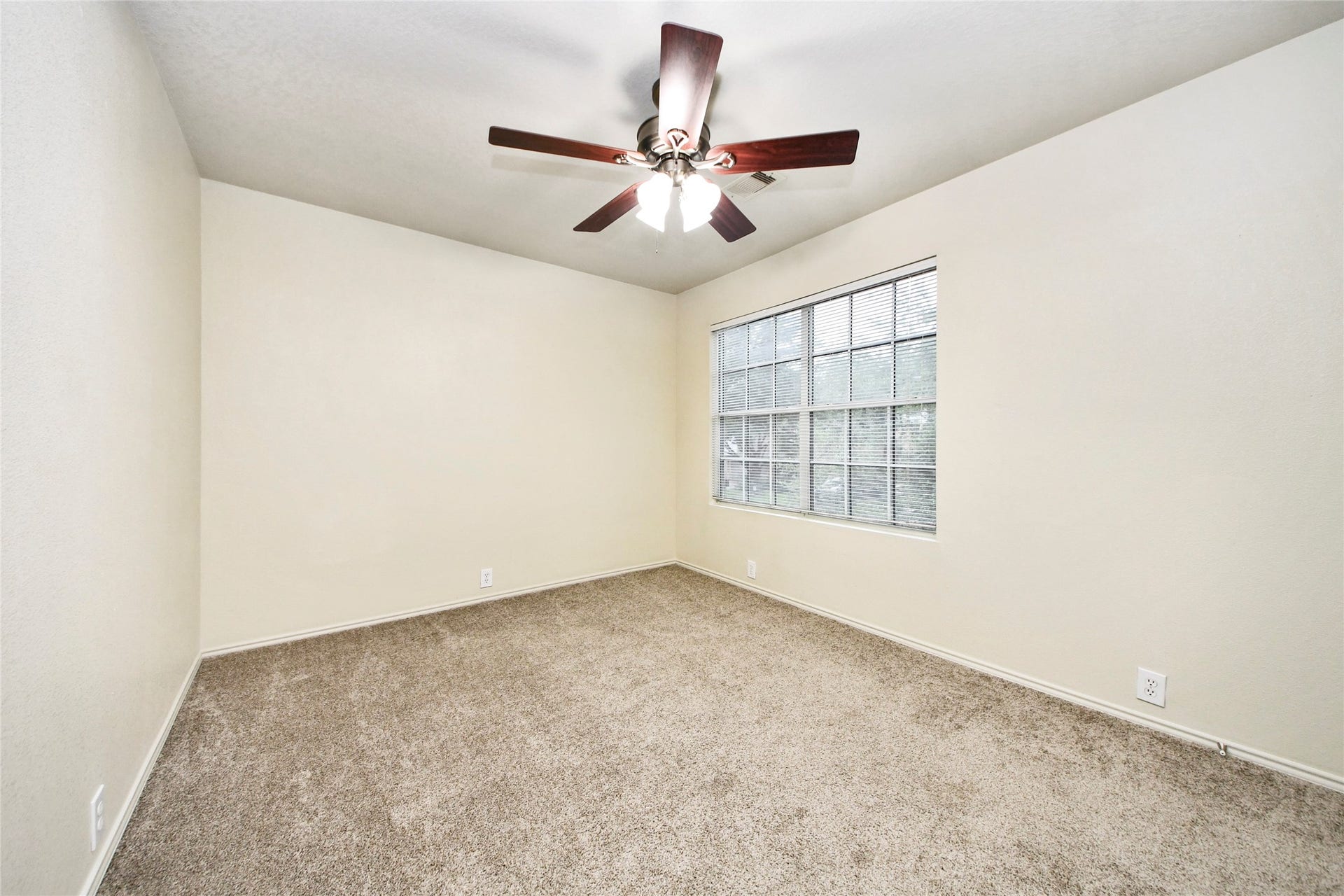 Bright and inviting, the second bedroom features plush carpeting, a large window for natural light, and a stylish ceiling fan for comfort.