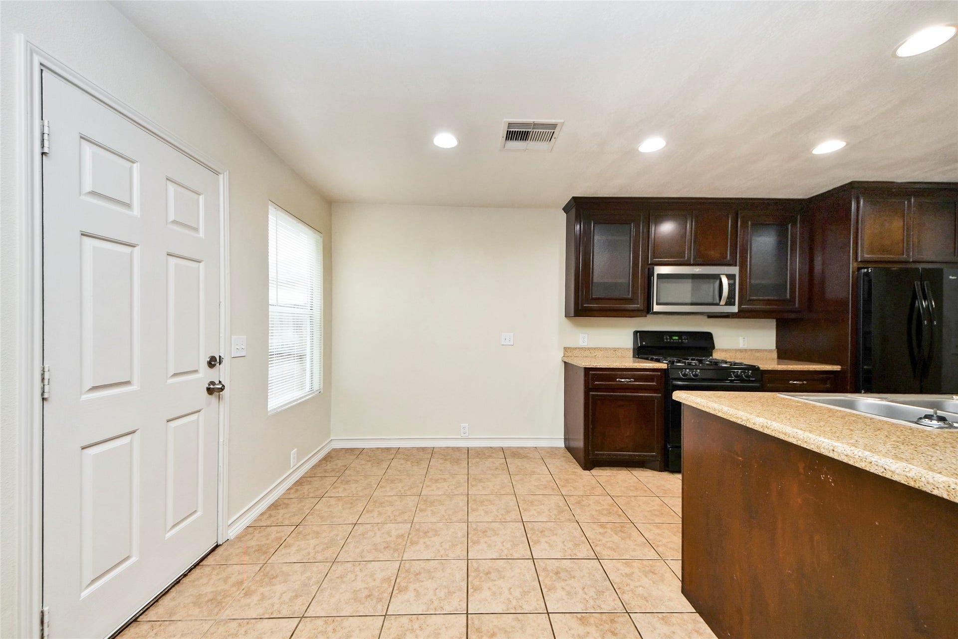 Bright and inviting, this breakfast area seamlessly connects to a modern kitchen with rich cabinetry and sleek appliances, perfect for morning gatherings.