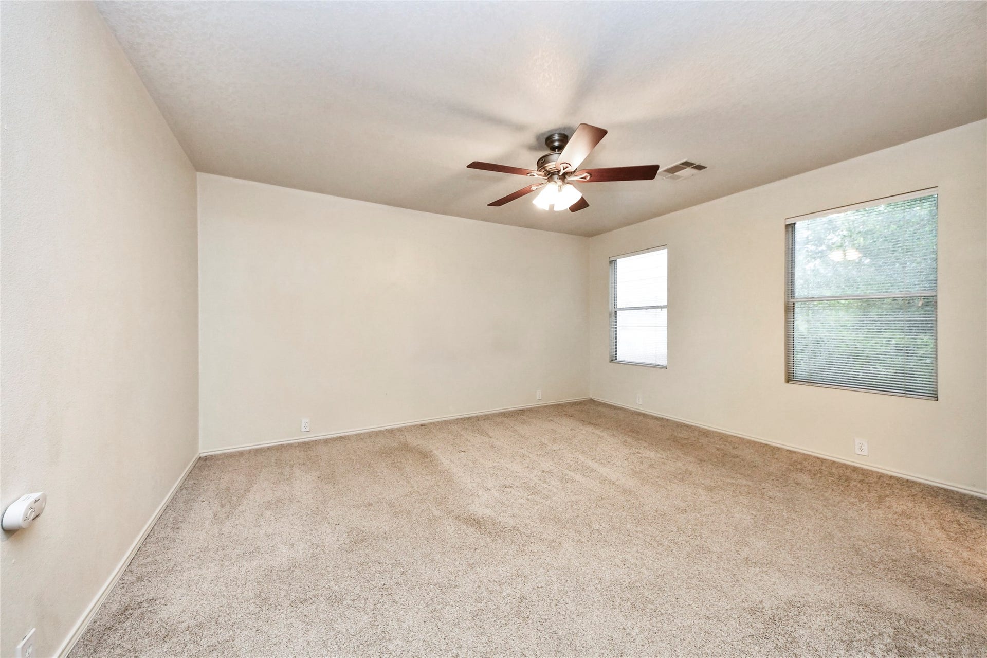 Spacious and inviting, this second-floor primary bedroom features plush carpeting, abundant natural light, and a stylish ceiling fan for ultimate comfort.