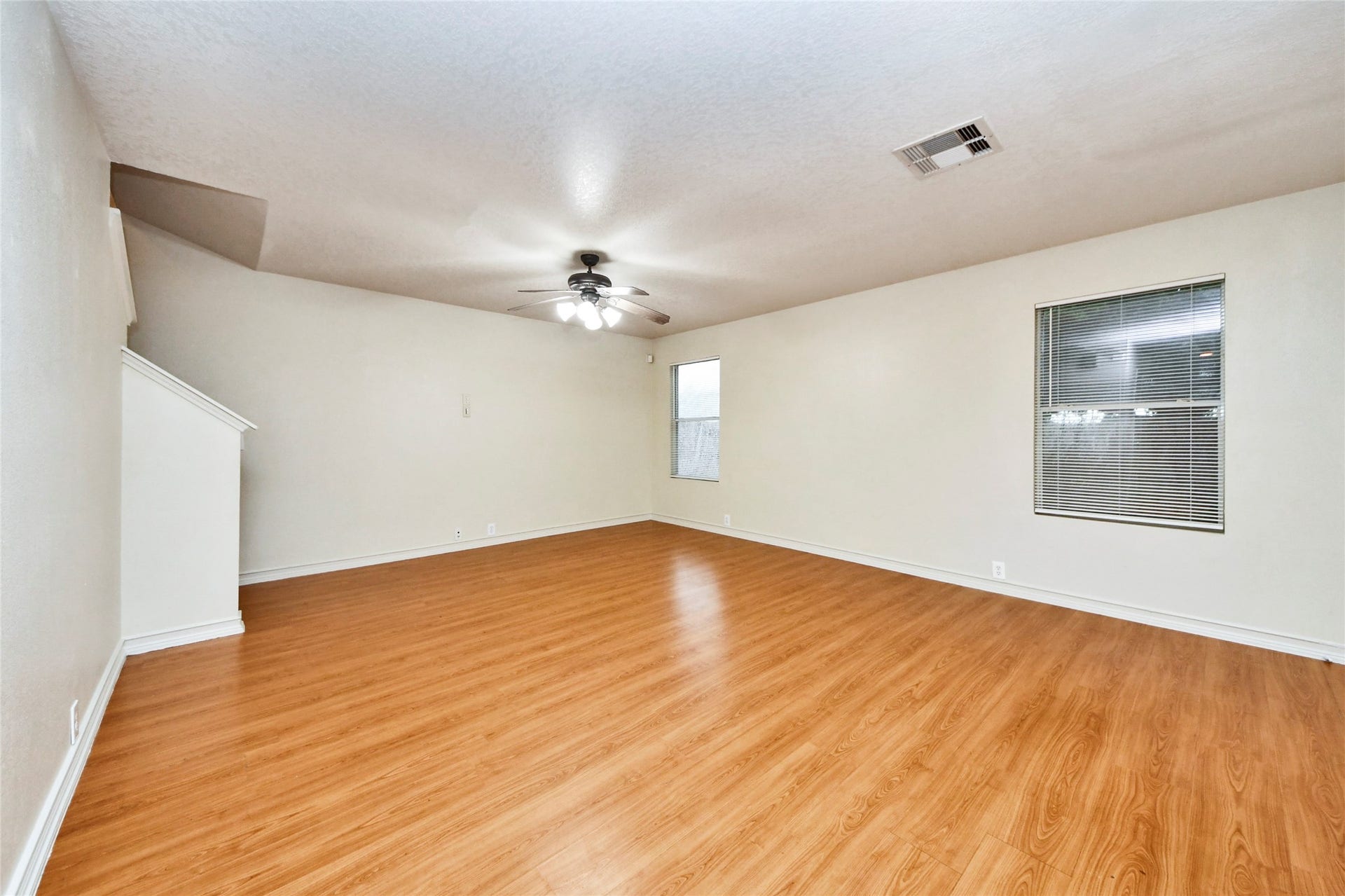 Spacious and inviting, this family room boasts warm wood flooring, abundant natural light, and a ceiling fan for comfort, creating the perfect setting for relaxation and gatherings.