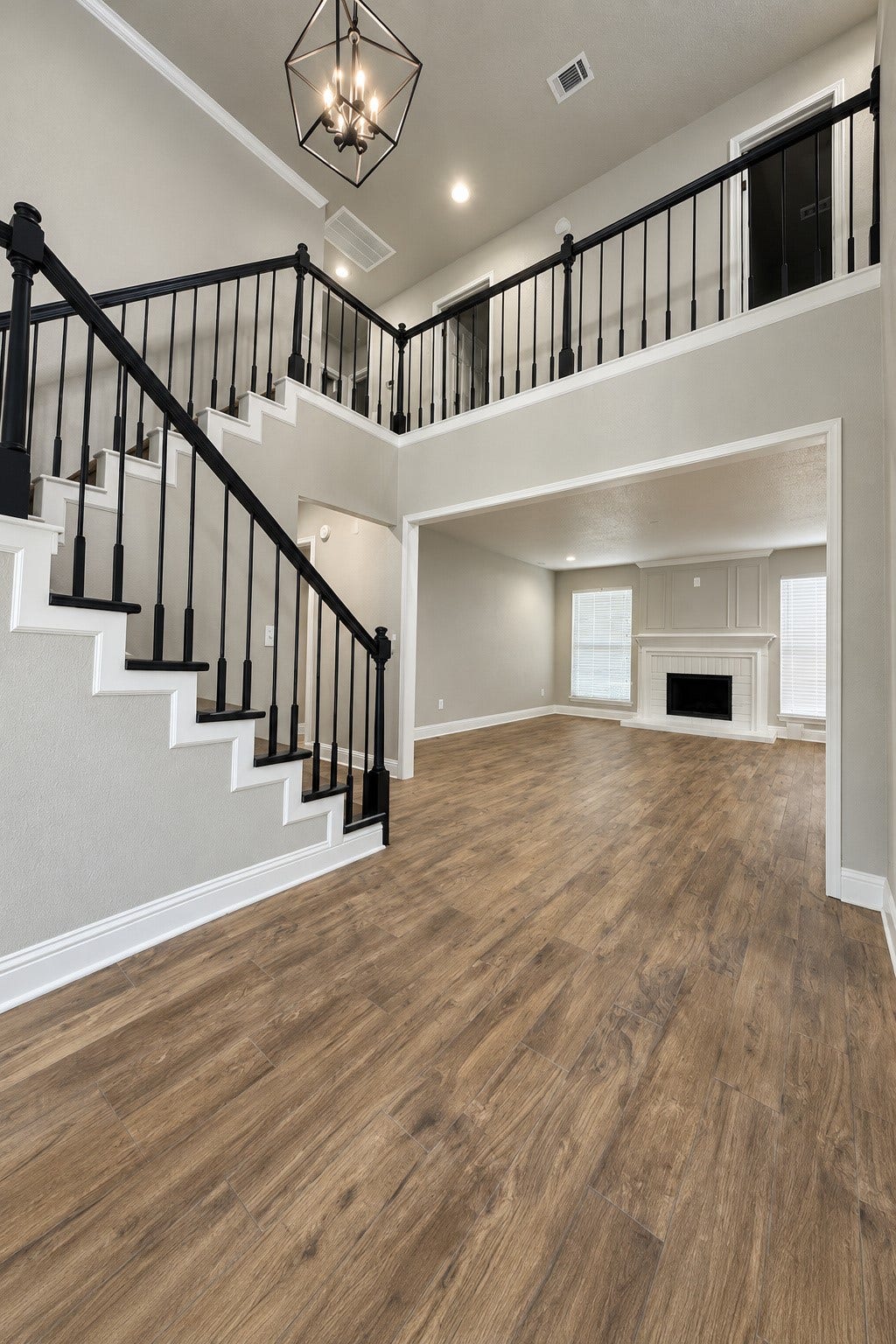 2102 Autumn Cove Drive, League City, TX 77573 Beautiful two-story entry featuring an elegant staircase with black railings, rich wood-look flooring, and an open view into the spacious living room with fireplace.