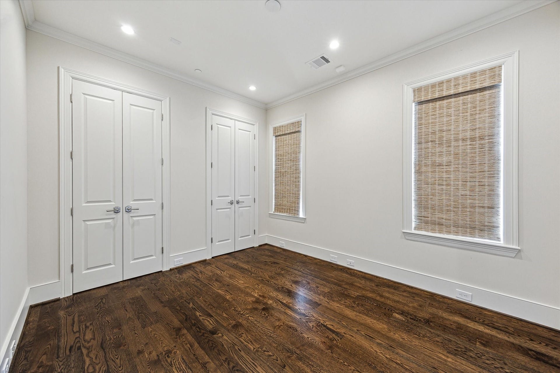 2413 Mimosa Drive, Houston, TX 77019 Tall windows, woven shades, dark hardwood floors, and two sets of paneled doors give this bedroom a clean architectural framework. There is plenty of wall space for art and furniture without sacrificing the rooms sense of openness.