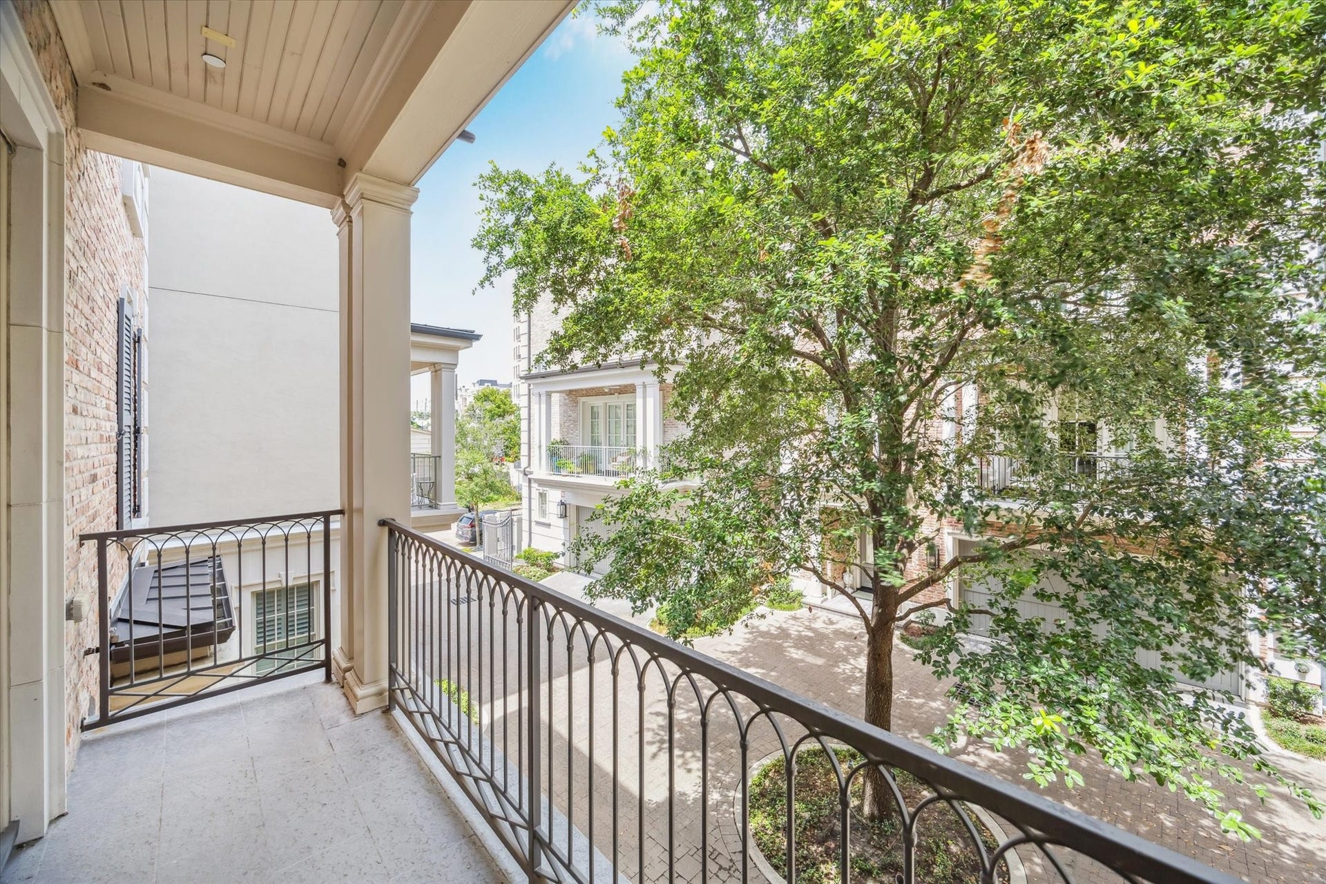 2413 Mimosa Drive, Houston, TX 77019 Step outside and the intimacy of the six-home enclave becomes clear. The covered balcony overlooks mature trees and neighboring residences, creating a surprisingly tucked-away moment just beyond the main living room.