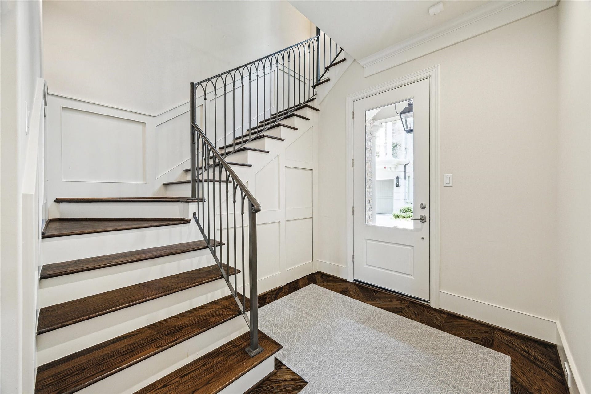 2413 Mimosa Drive, Houston, TX 77019 A wider look at the stair hall shows how thoughtfully the home uses its circulation spaces. Crown molding, paneled millwork, hardwood floors, and the sculptural iron railing give even the passage between rooms a finished point of view.
