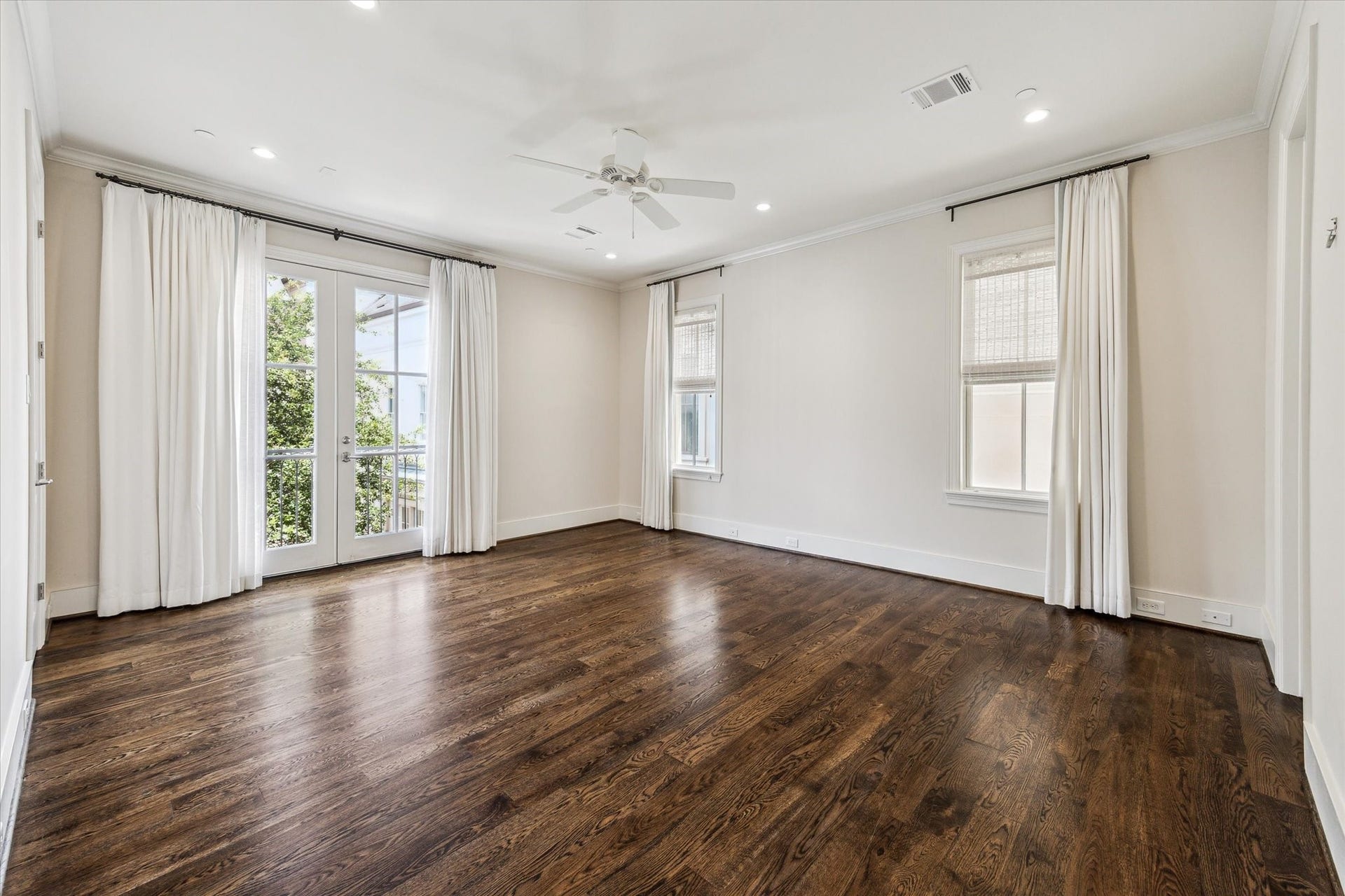 2413 Mimosa Drive, Houston, TX 77019 Upstairs, the primary suite feels noticeably removed from the activity of the main living level. Hardwood floors continue underfoot, while windows on multiple sides and French doors to a Juliet balcony fill the room with natural light.