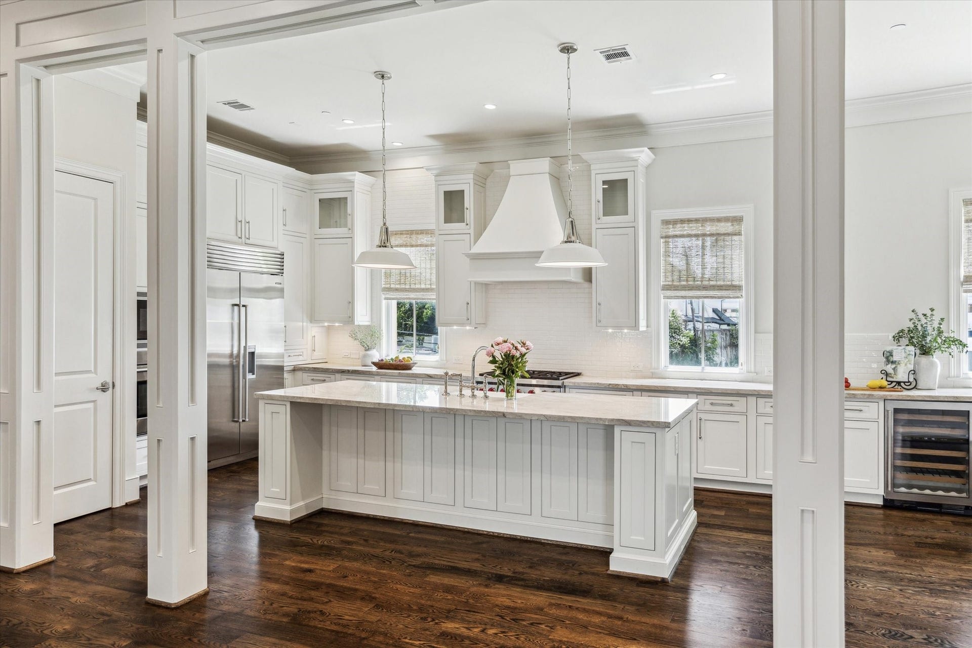 2413 Mimosa Drive, Houston, TX 77019 The kitchen is centered around a substantial island designed to do more than one job. A farmhouse sink, broad stone work surface, seating, and storage make it equally suited to morning coffee, meal prep, or having everyone gather in one place.