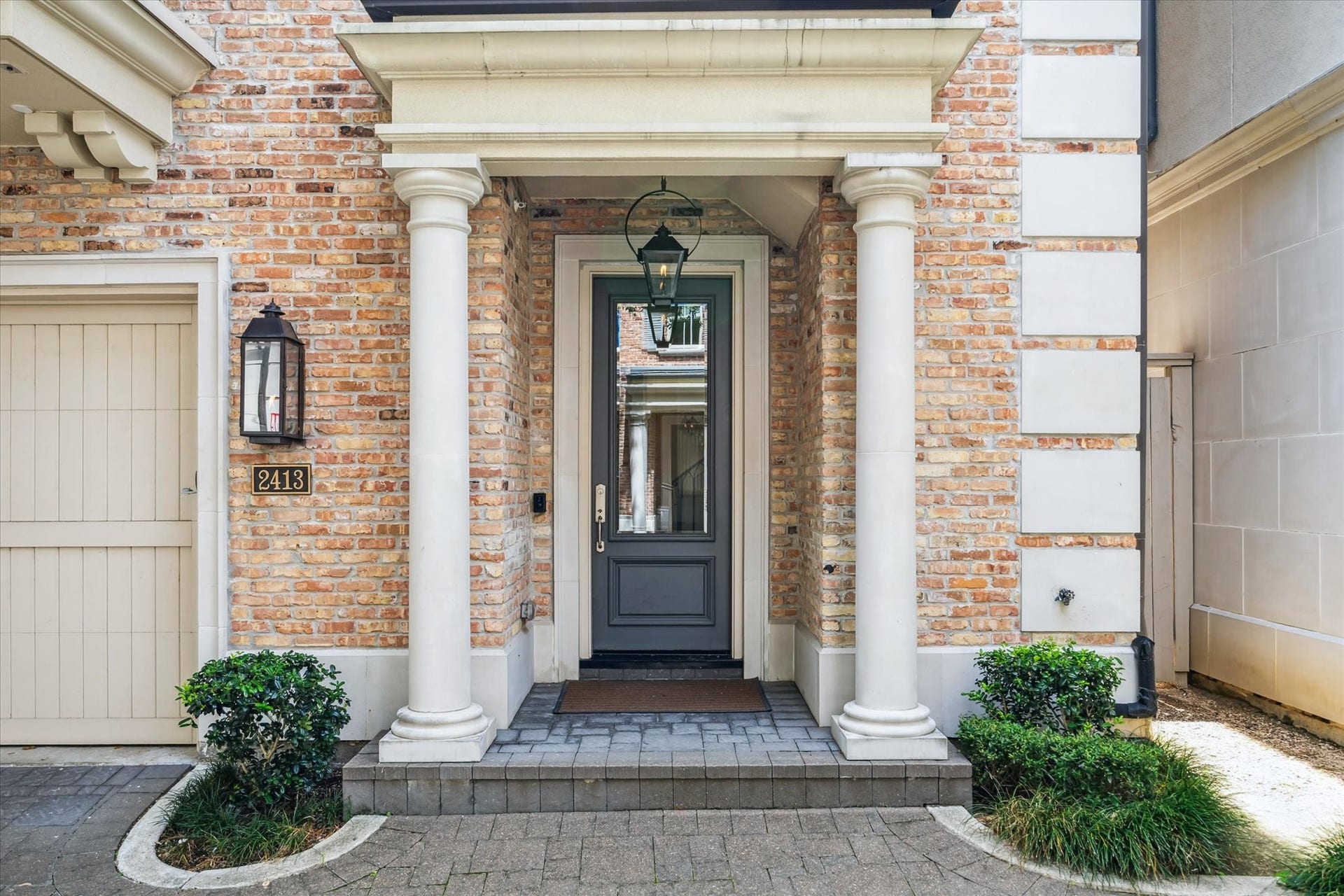2413 Mimosa Drive, Houston, TX 77019 The approach is classic and understated. Reclaimed-look brick, substantial columns, a hanging lantern, and a deep-set front door create an entrance that feels established rather than overly formal.