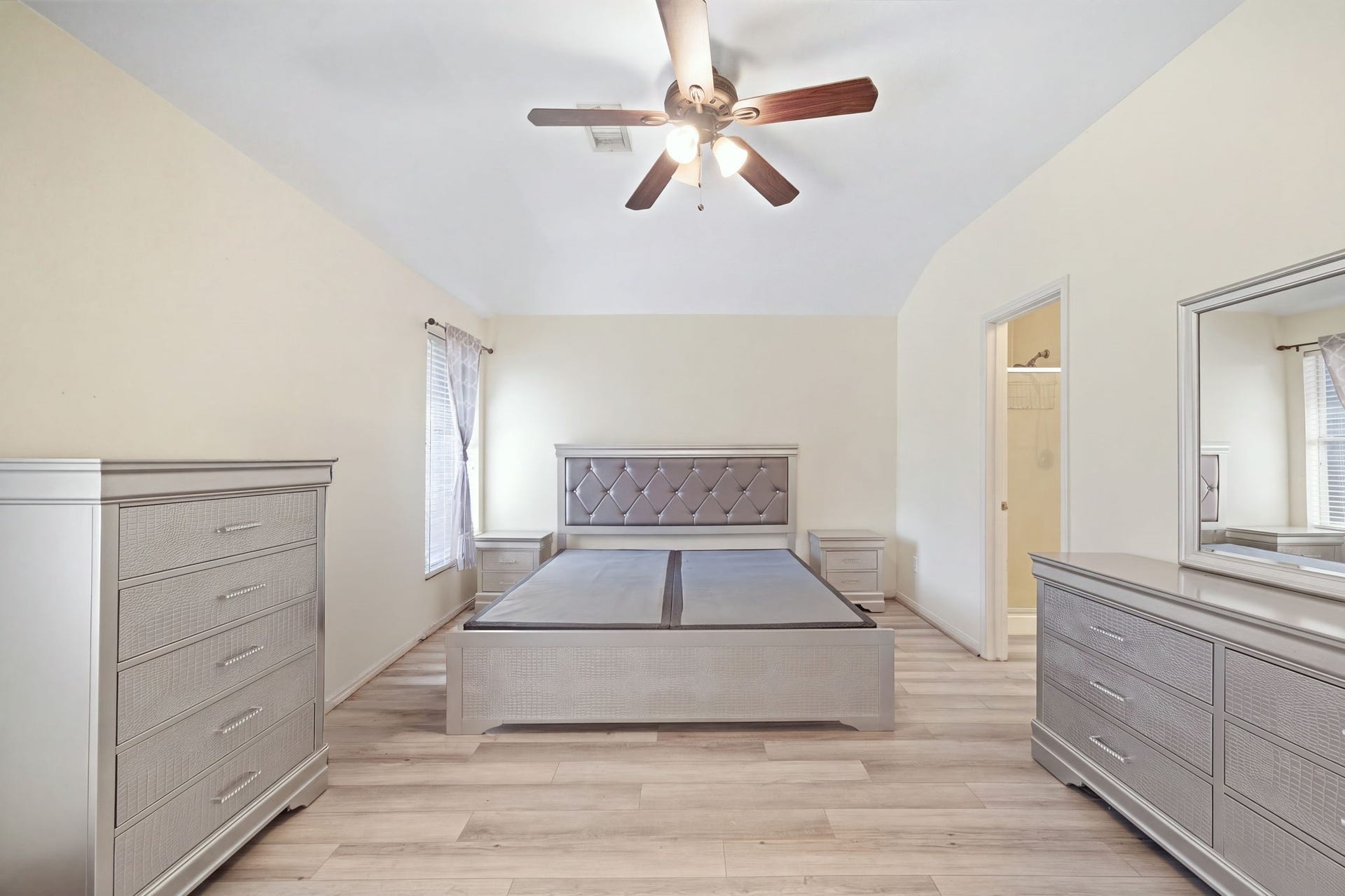 Restful and generously scaled, the primary bedroom showcases durable wood-look flooring, neutral walls, and a cooling ceiling fan. The well-proportioned layout accommodates substantial furnishings and opens directly into the private ensuite bath for everyday ease.
