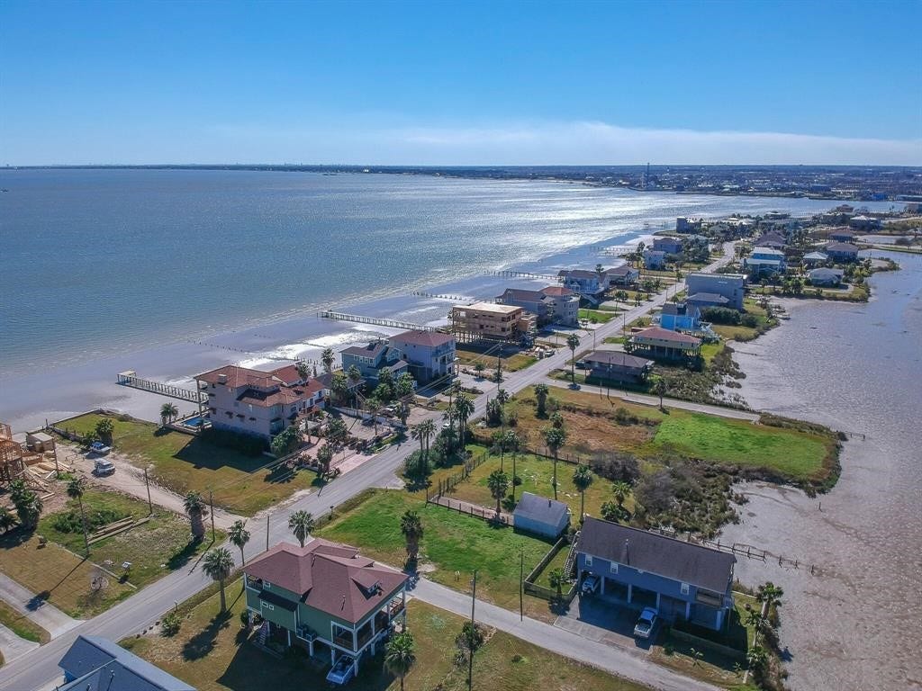 1816 - TBDT Todville Road, Seabrook, TX 77586 This aerial view showcases a serene coastal neighborhood with waterfront homes, each offering stunning views of the expansive bay. The area features lush greenery and well-maintained roads. Ideal for seaside living.