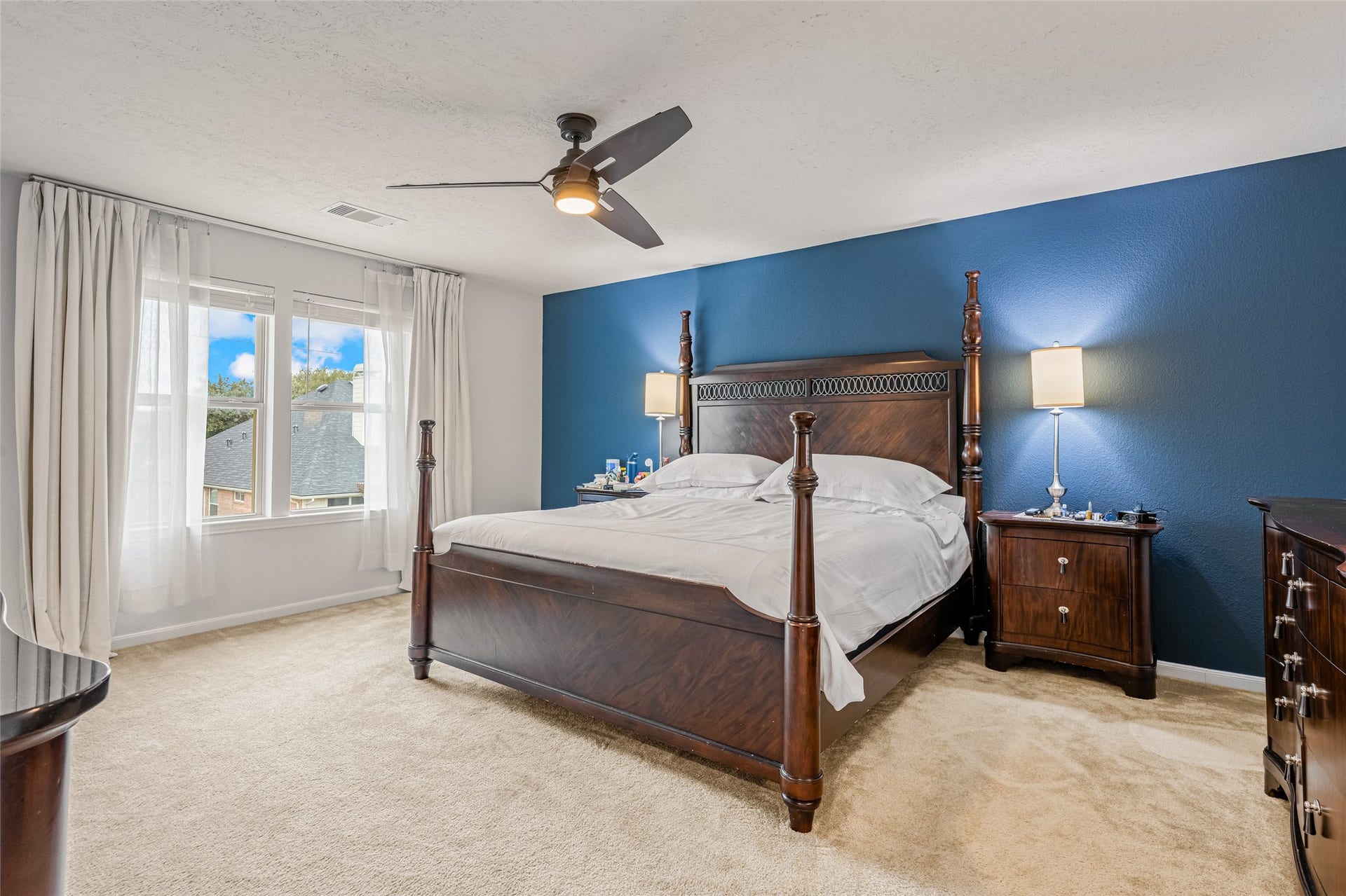 3806 Belmore Lane, Pearland, TX 77584 Natural light fills your primary bedroom, while the deep blue accent wall adds a rich backdrop to a peaceful space made for unwinding.