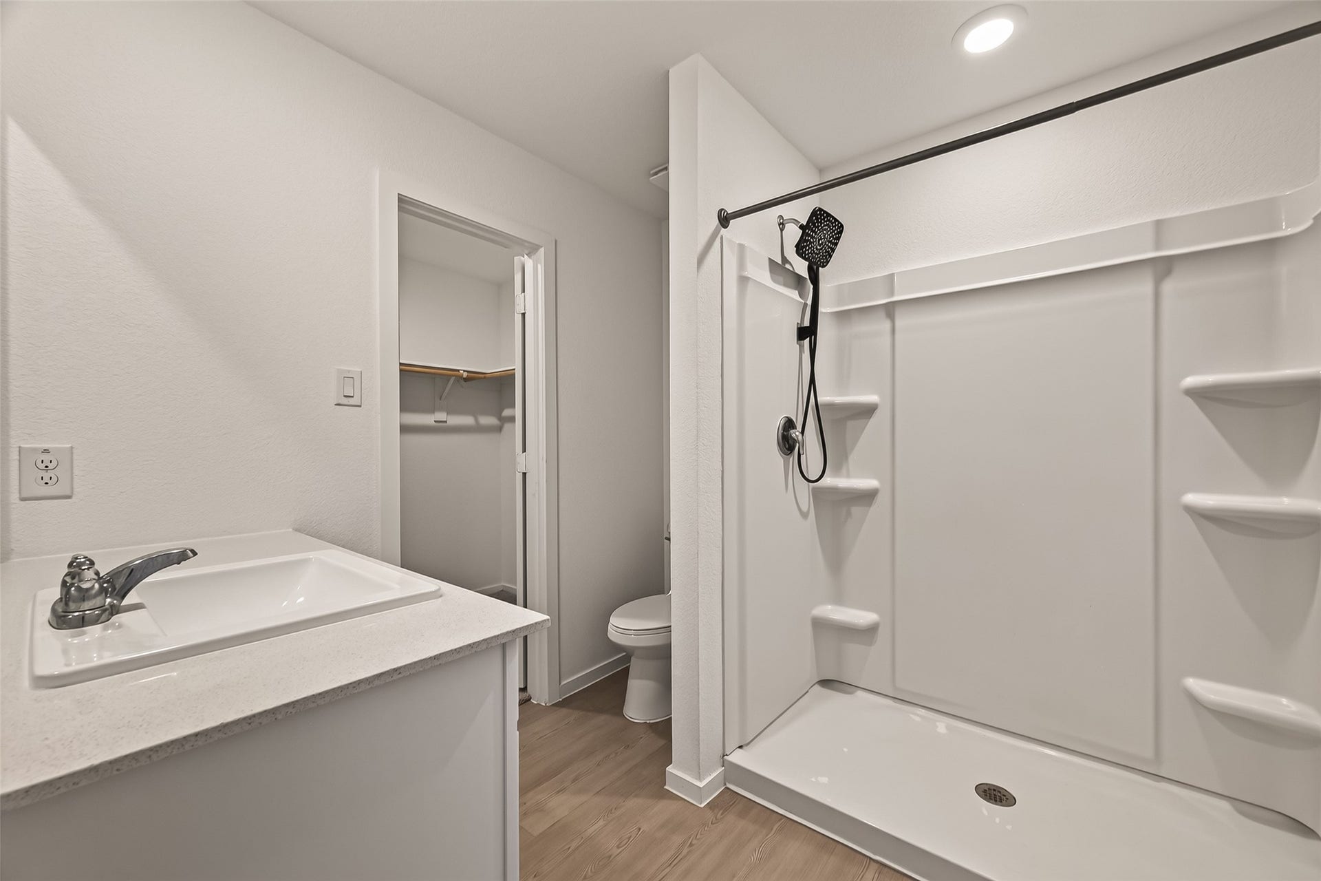 7814 Lavender Jade Drive, Rosharon, TX 77583 The primary bathroom features an oversized walk-in shower equipped with a rainfall showerhead and convenient built-in shelving, complemented by a durable Corian countertop.