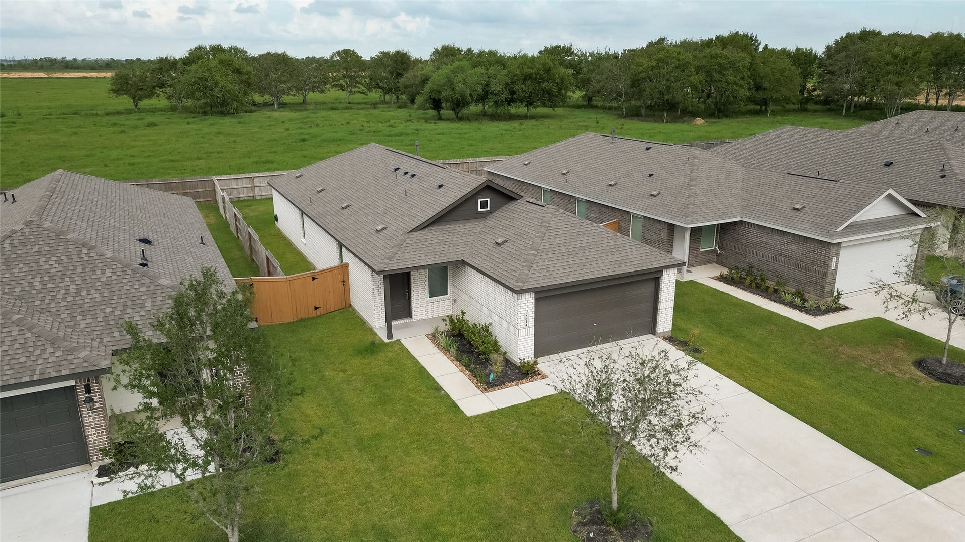 7814 Lavender Jade Drive, Rosharon, TX 77583 This aerial view highlights the one-year-old roof, the professional landscaping, and the expansive green space situated behind the property.