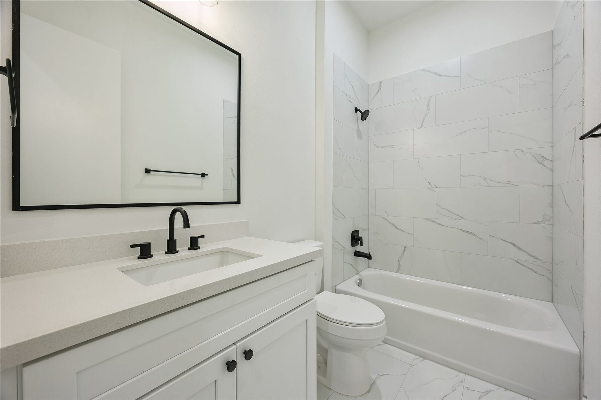 The secondary bedroom's ensuite bath is equally well appointed, featuring quartz countertops, designer tile, and a tub/shower combination.