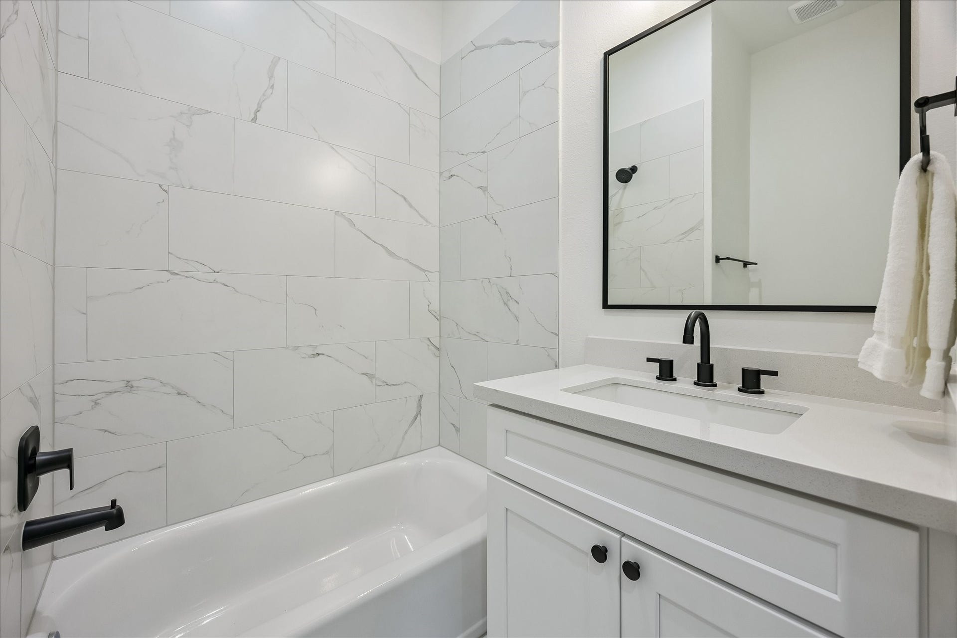 The ensuite first-floor bath showcases stylish tile, quartz countertops, and a tub/shower combination.