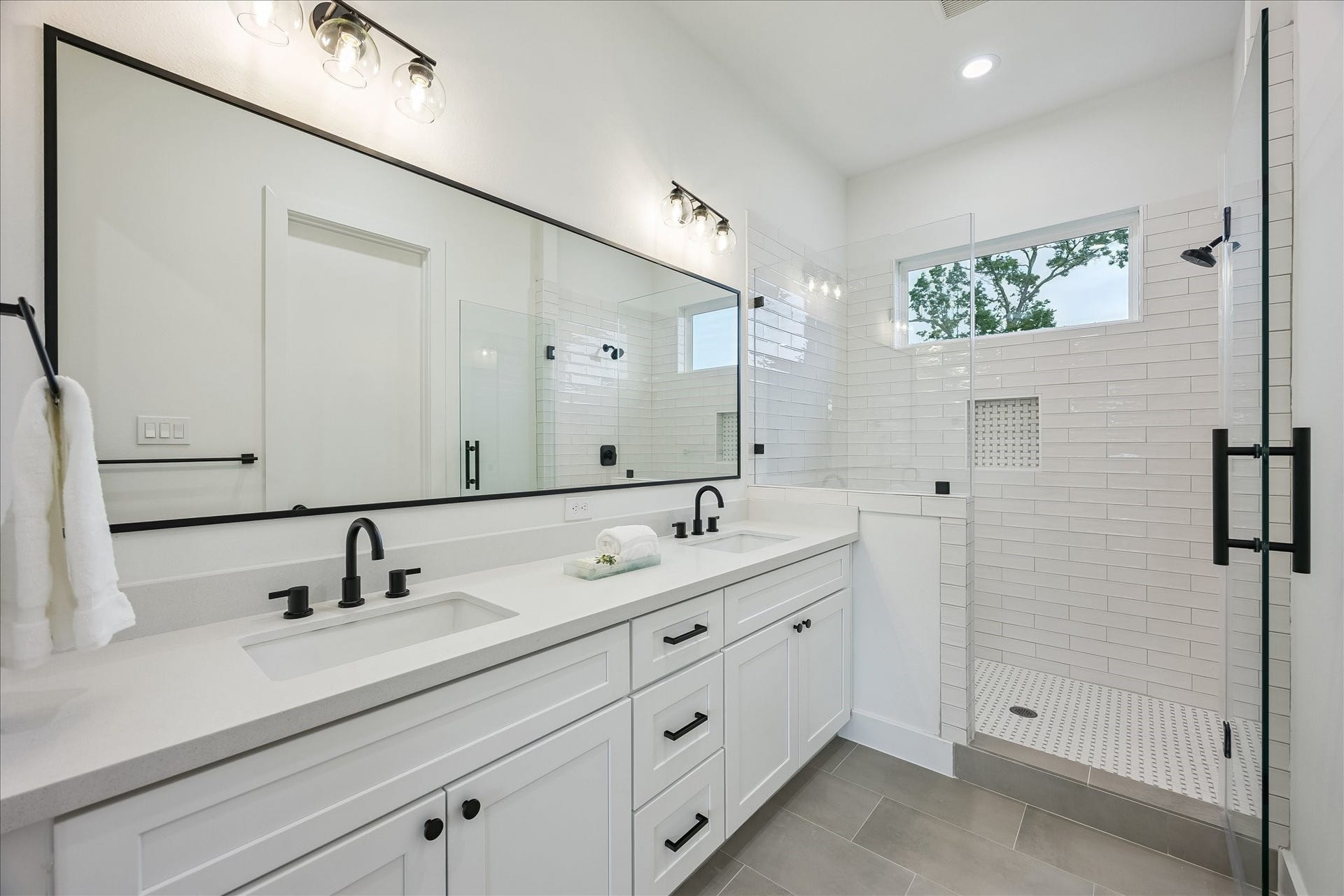 The spa-inspired primary bath features dual vanities and a spacious walk-in shower with a built-in bench. Designer tilework and a convenient shampoo niche add the perfect finishing touches.