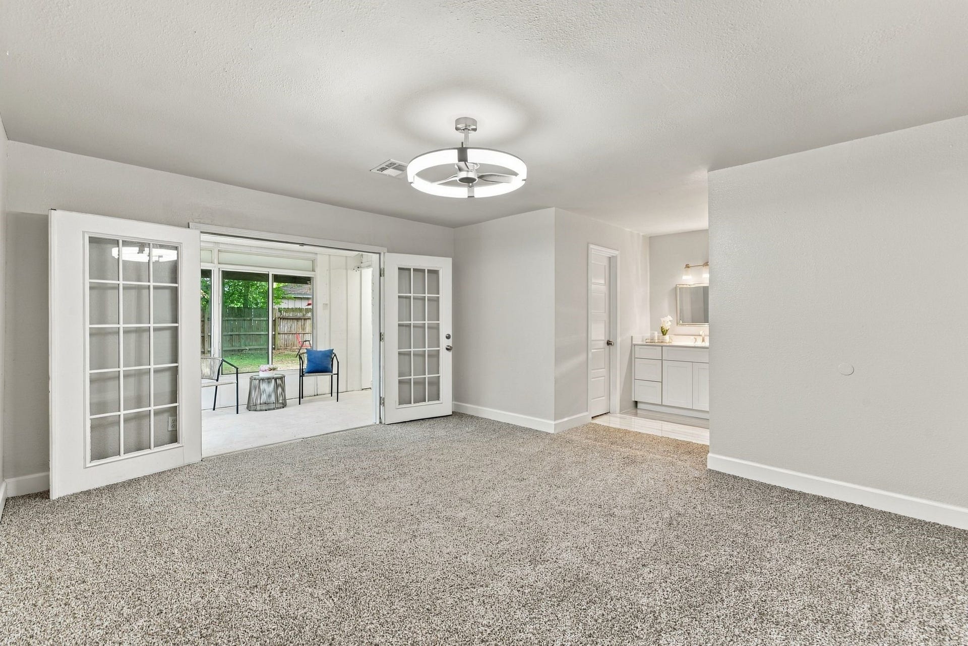 Primary bedroom with french doors leading to an outdoor patio.