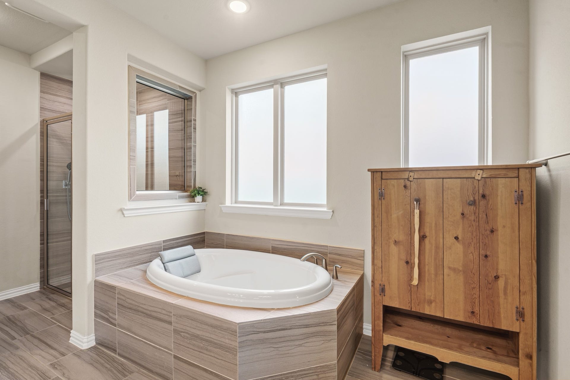 A closer look at the spa-inspired soaking tub reveals premium tile surrounds and plenty of natural, diffused light from the large privacy-glass windows.
