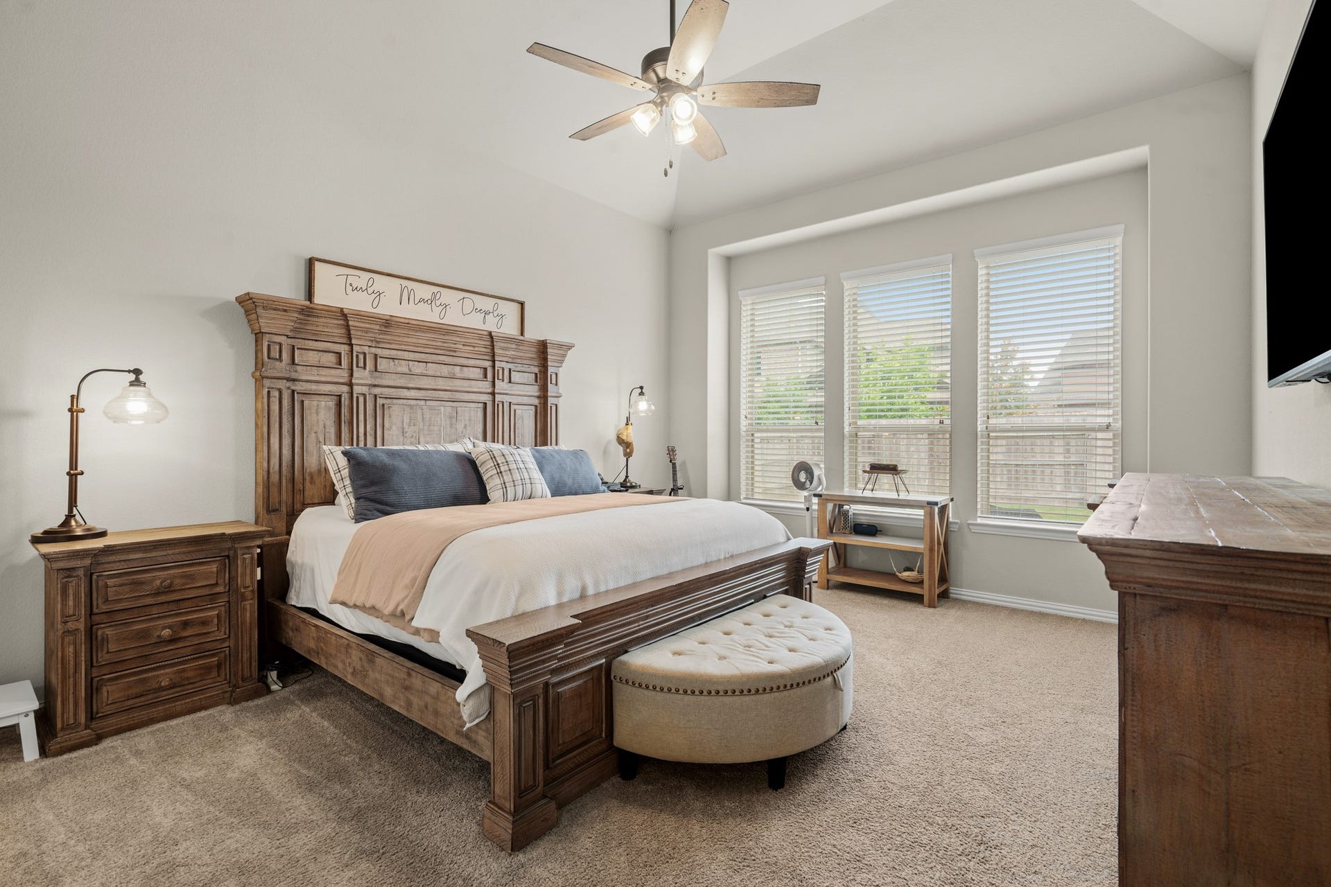 A grand view of the primary suite demonstrates its extensive layout, highlighting a deeply recessed window wall, high vaulted ceilings, and ample room for substantial bedroom furnishings.