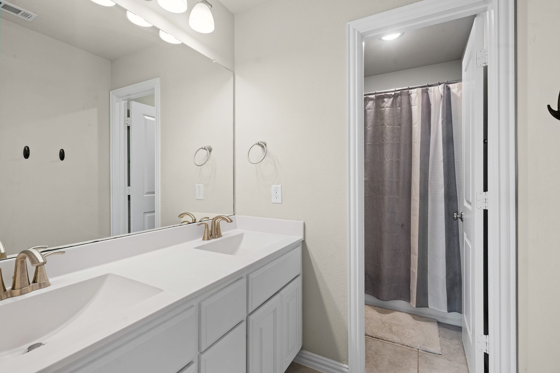 A look into the upstairs bathroom, offering a long dual-sink vanity with plenty of lower cabinet storage and modern fixtures.