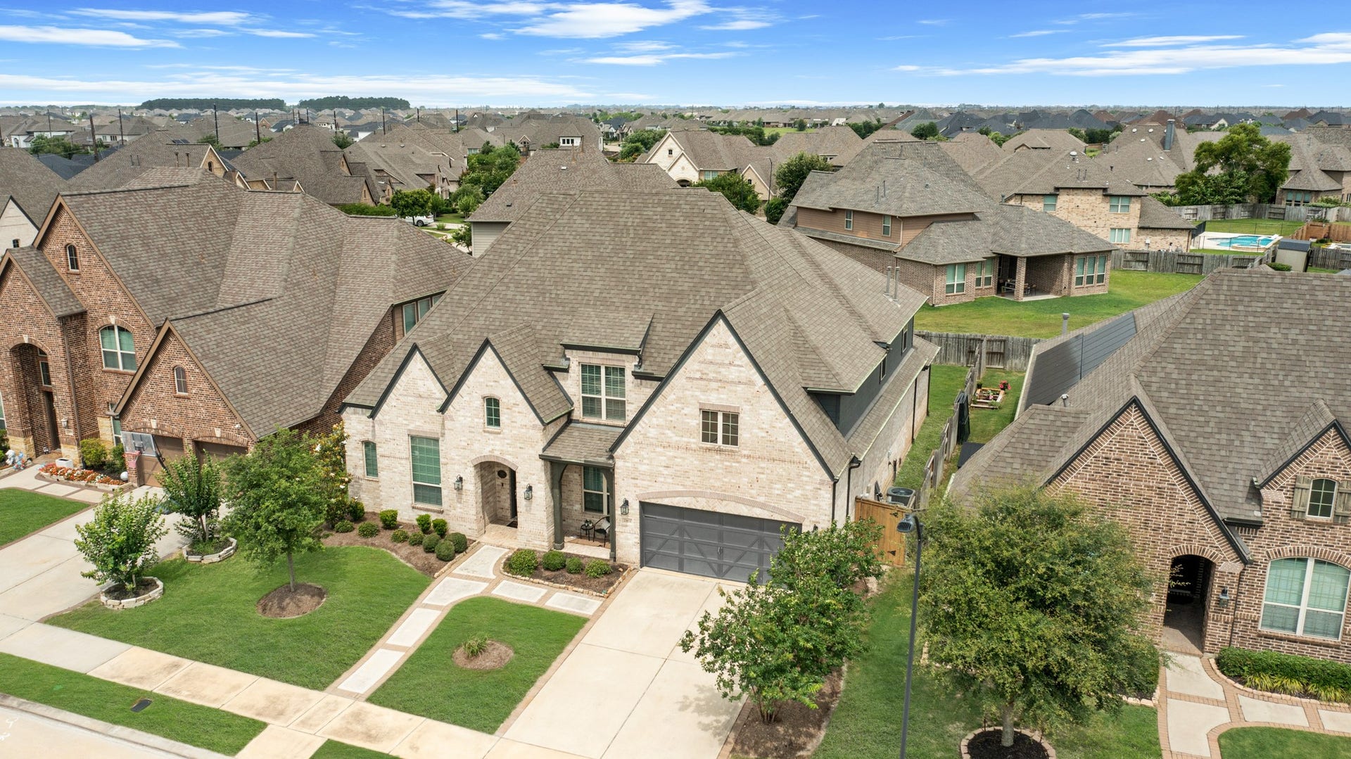 A high-angle perspective highlights the deep lot size and the extra-wide driveway leading to the 3-car garage.