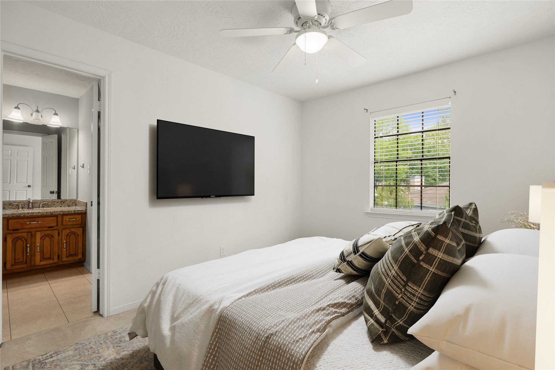 8007 Suspiro Drive, Houston, TX 77083 Spacious secondary bedroom featuring high ceilings, ceiling fan, plush carpet flooring, and private vanity area into shared secondary bathroom. *Virtually Staged