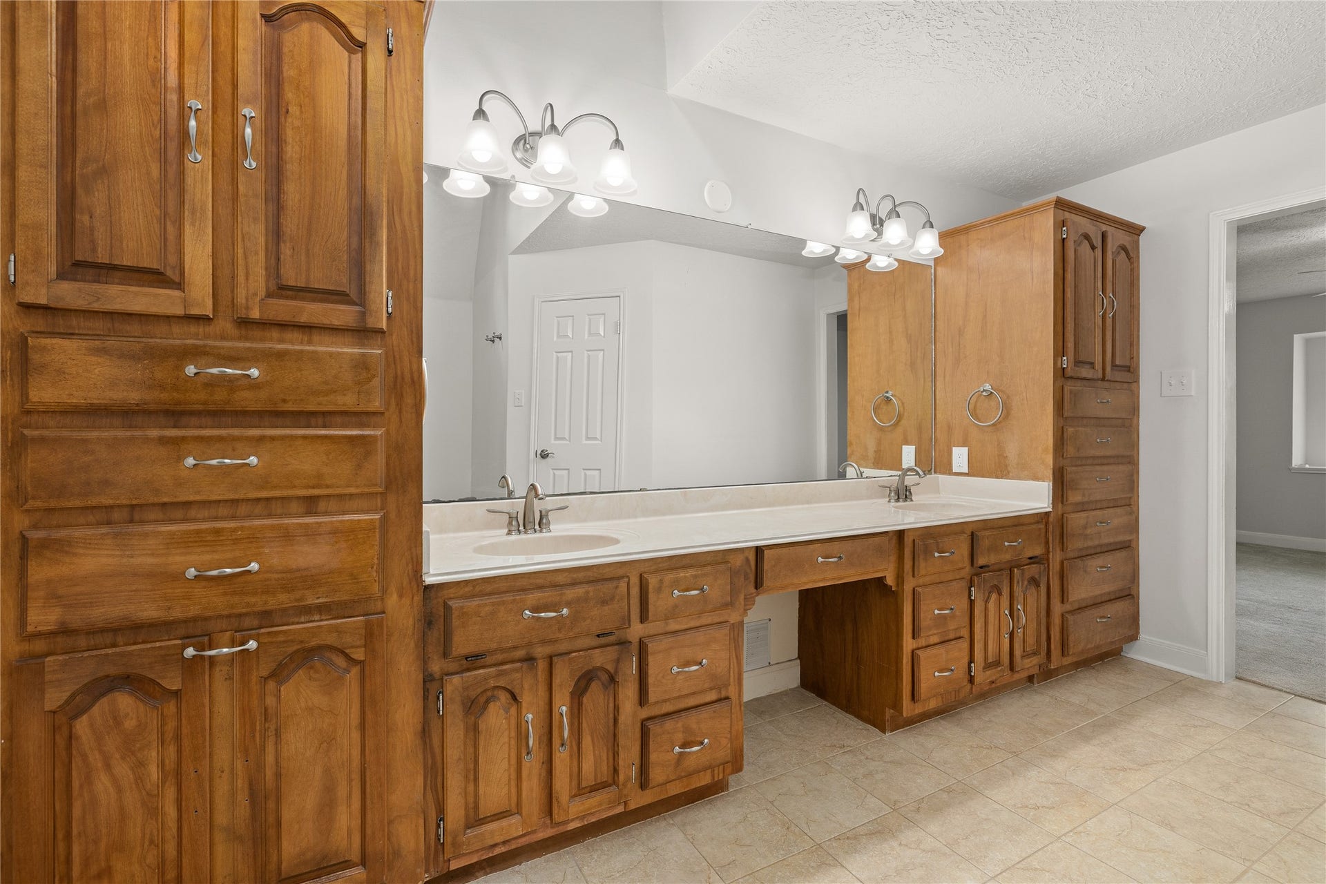 8007 Suspiro Drive, Houston, TX 77083 The primary bathroom offers a spa-like retreat with an expansive double vanity and an abundance of custom storage. This well-appointed space features warm wood cabinetry and a thoughtful layout designed for both luxury and daily convenience.