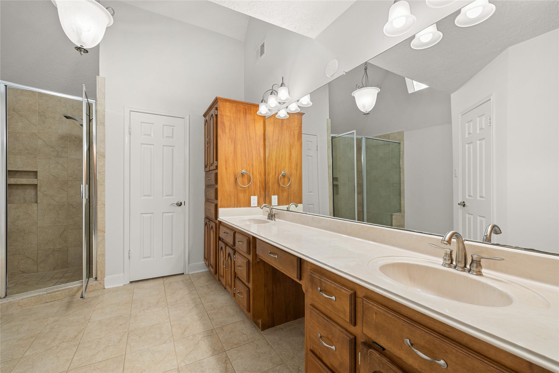 8007 Suspiro Drive, Houston, TX 77083 This additional perspective reveals the impressive scale of the primary bath, highlighting its soaring ceilings and premium amenities. The space is anchored by a glass-enclosed walk-in shower and a sprawling vanity, creating a luxurious and functional ensuite experience.