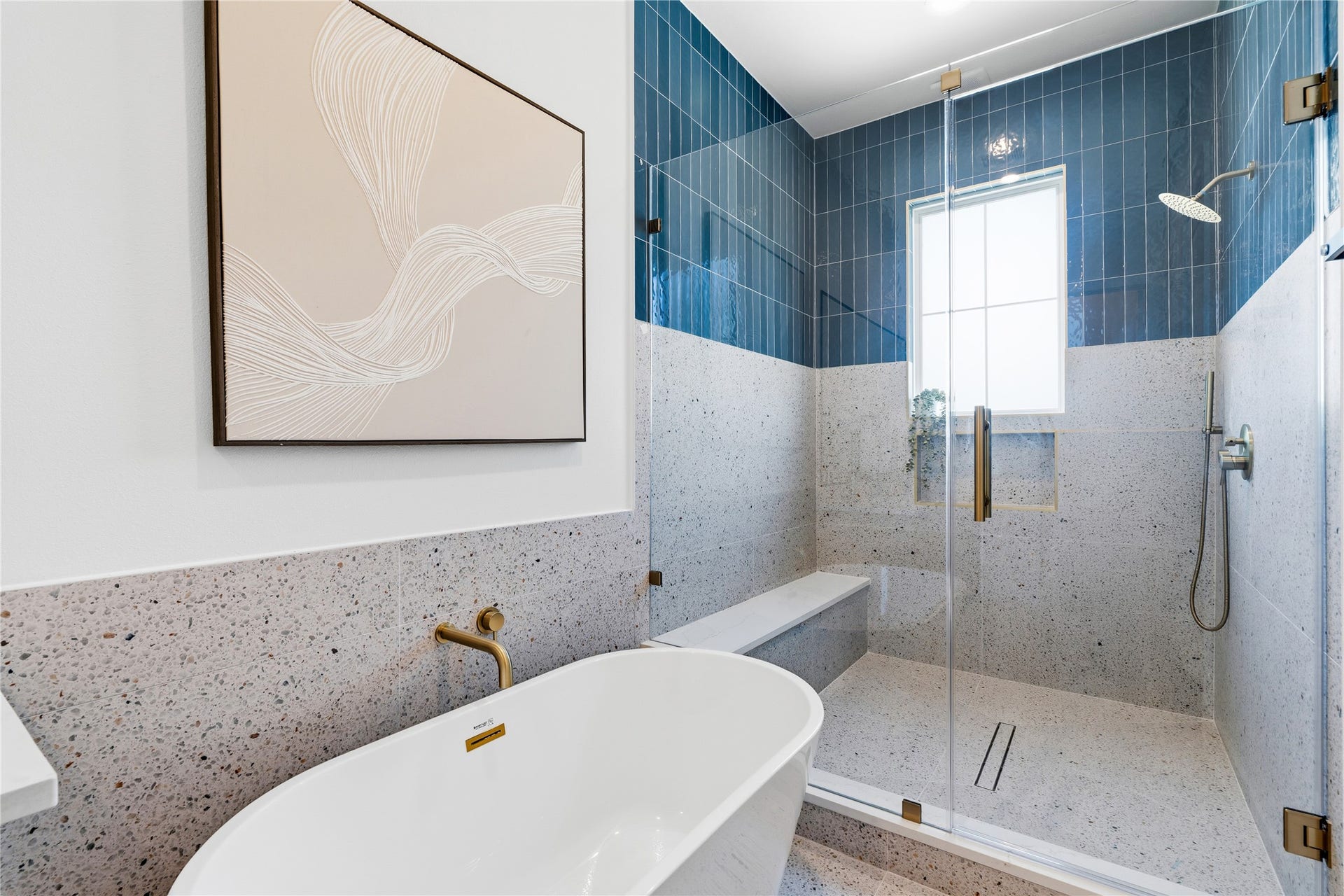 4610 Gunter Street, Houston, TX 77020 The shower area features a high-contrast combination of terrazzo-style stone and deep blue vertical tiling. Brushed gold hardware and a wall-mounted faucet elevate the sleek, contemporary aesthetic.