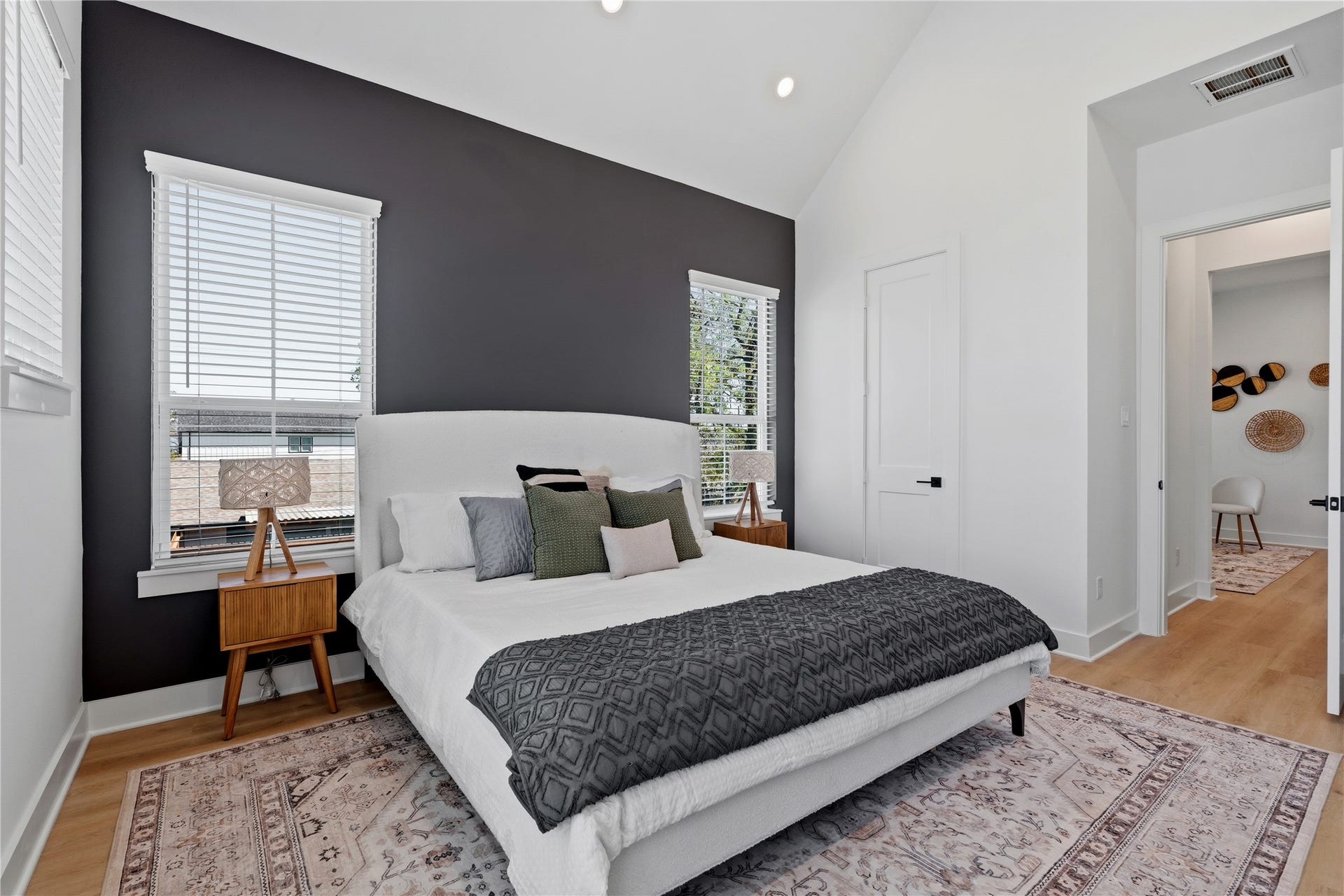4610 Gunter Street, Houston, TX 77020 A dramatic vaulted ceiling provides significant vertical volume to this primary suite. The deep charcoal accent wall creates a bold, structural focal point against the crisp white surfaces.