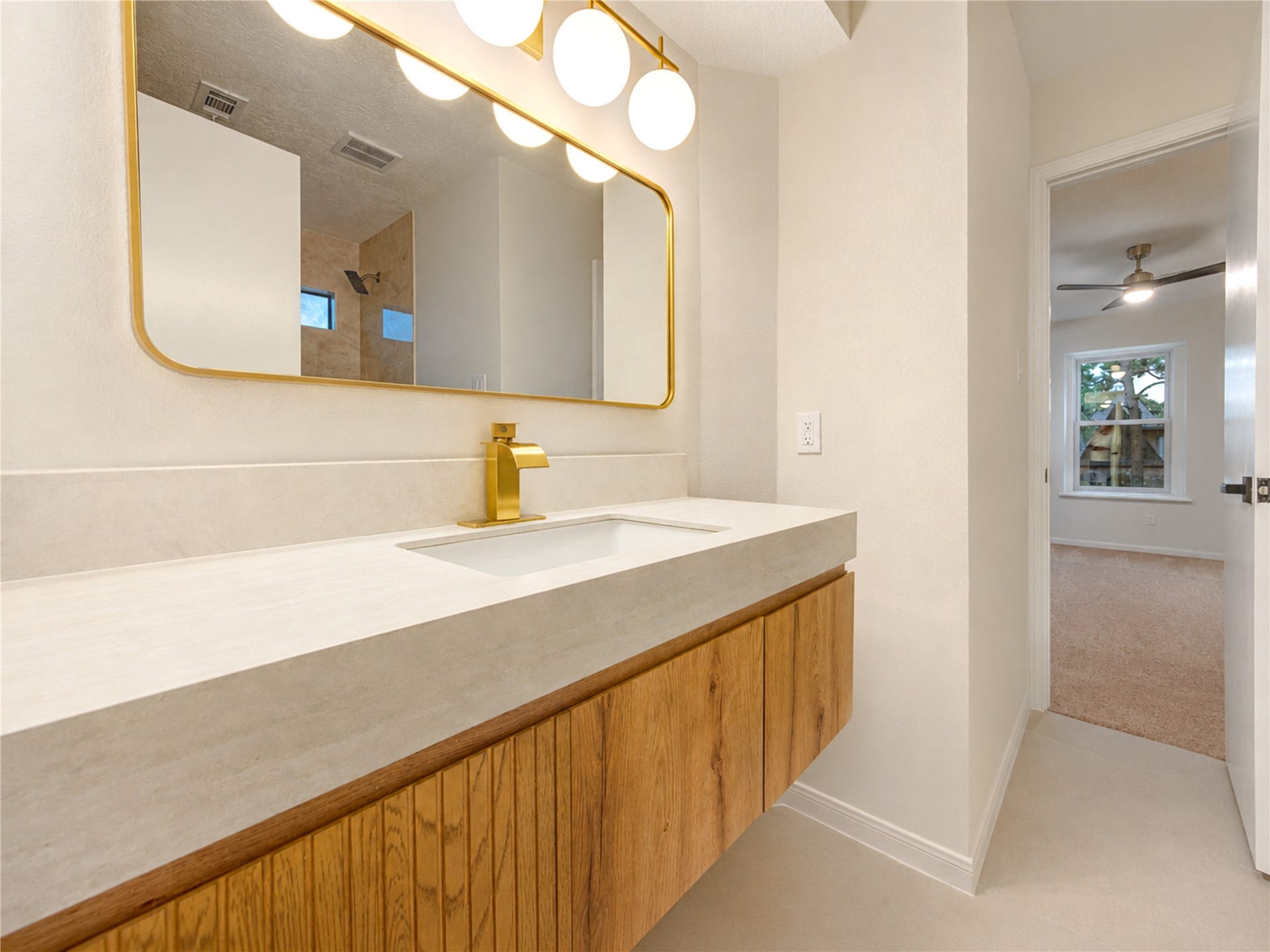 Updated Hollywood-style bath combines modern finishes with everyday functionality, featuring a sleek vanity, generous counter space and stylish gold accents. The convenient shared layout provides easy access between the upstairs bedrooms while still giving family members or guests their own space to get ready.