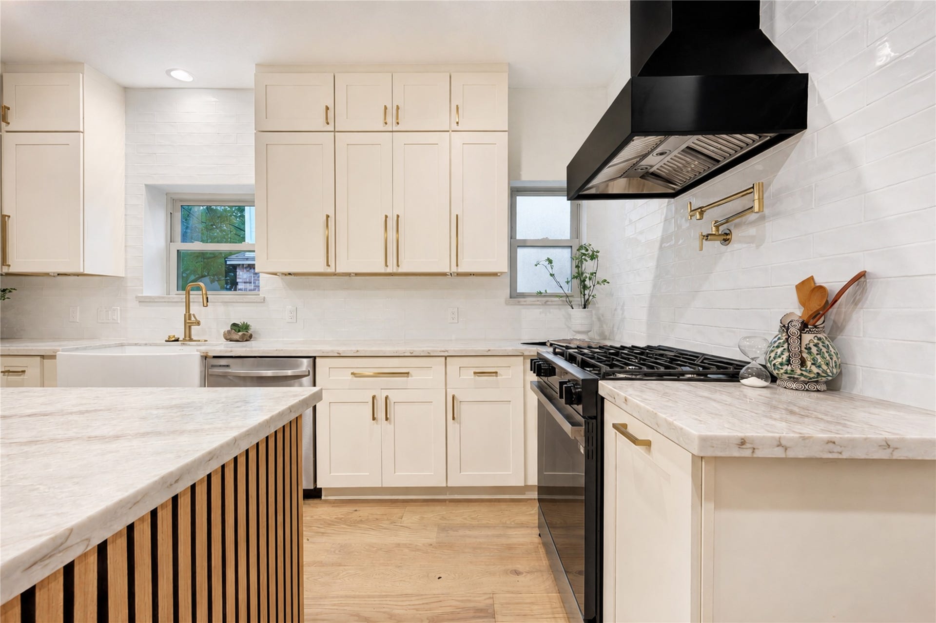 Another view of the beautifully renovated kitchen highlights abundant Shaker-style cabinetry, generous quartzite counter space and the statement gas range with vent hood. Thoughtfully designed for the rhythm of everyday life, theres plenty of room to prep dinner, serve a crowd and keep everything organized while staying connected to family and guests.