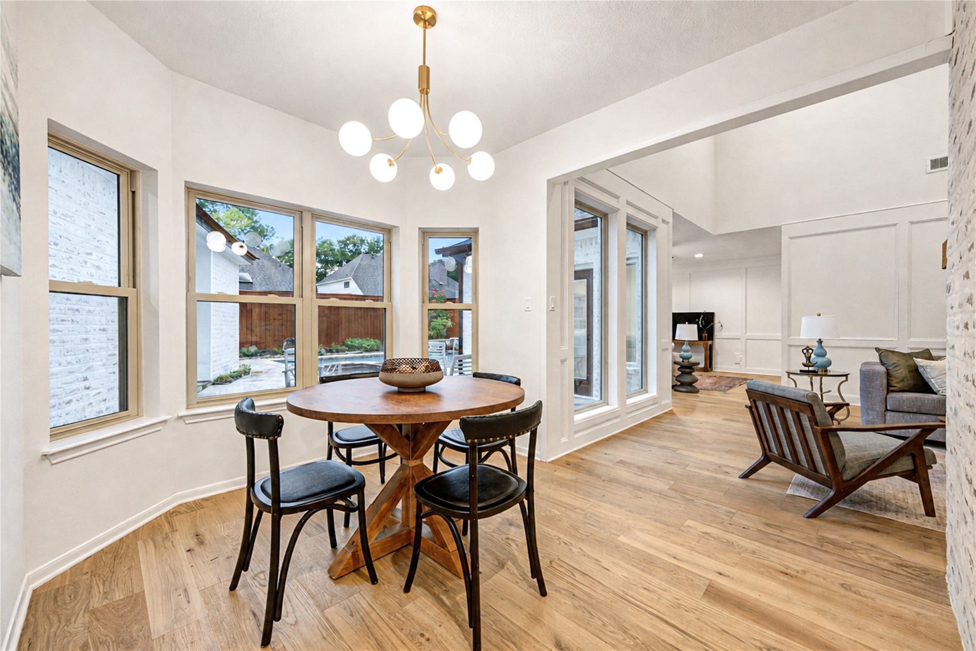 Light-filled dining area surrounded by expansive energy efficient windows, offering beautiful backyard views and an inviting setting for casual meals, dinner parties and memorable gatherings.