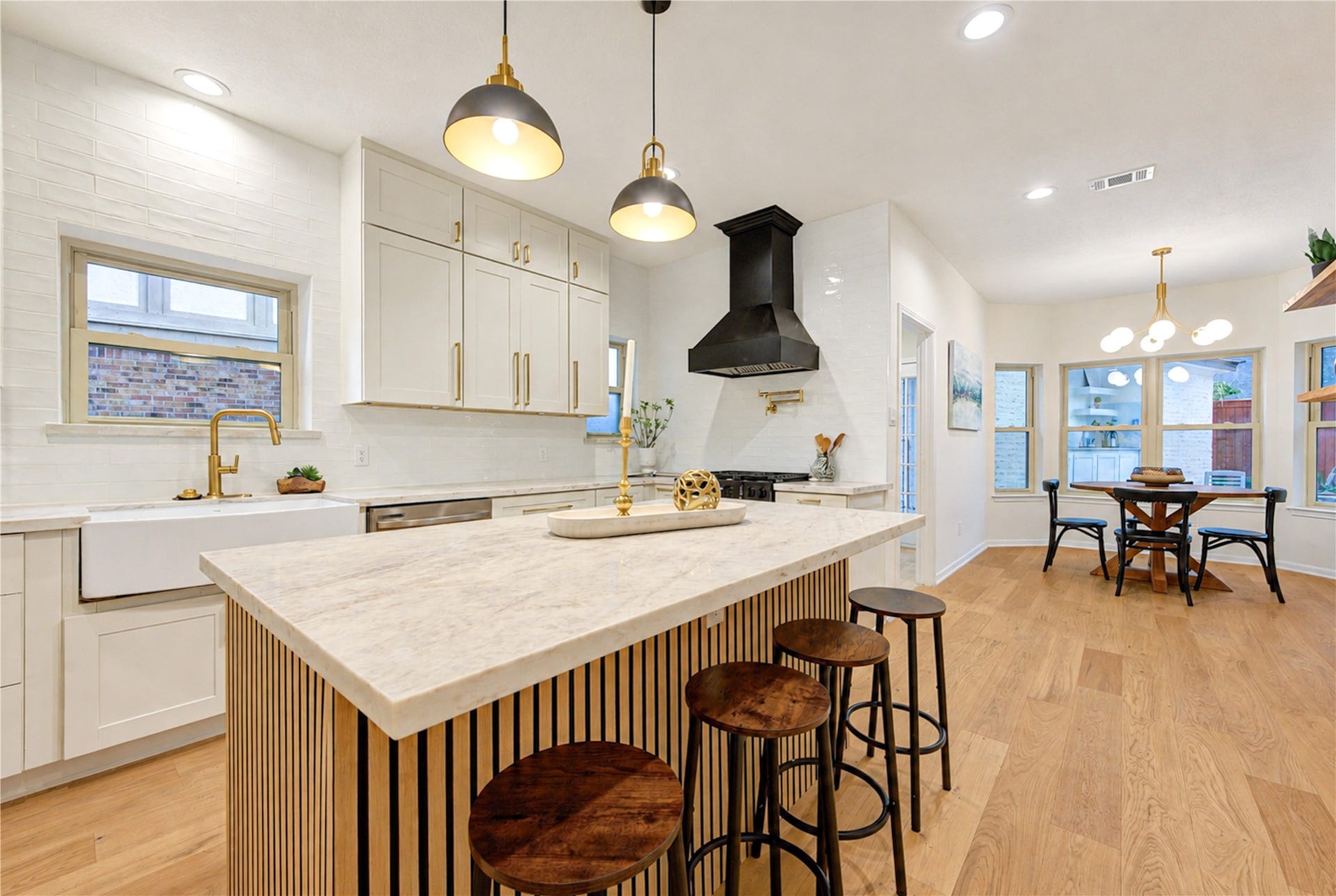 Completely redesigned kitchen featuring quartzite countertops, a large gathering island with seating, pendant lighting and a gas range, creating a bright, stylish space for everyday living and entertaining.