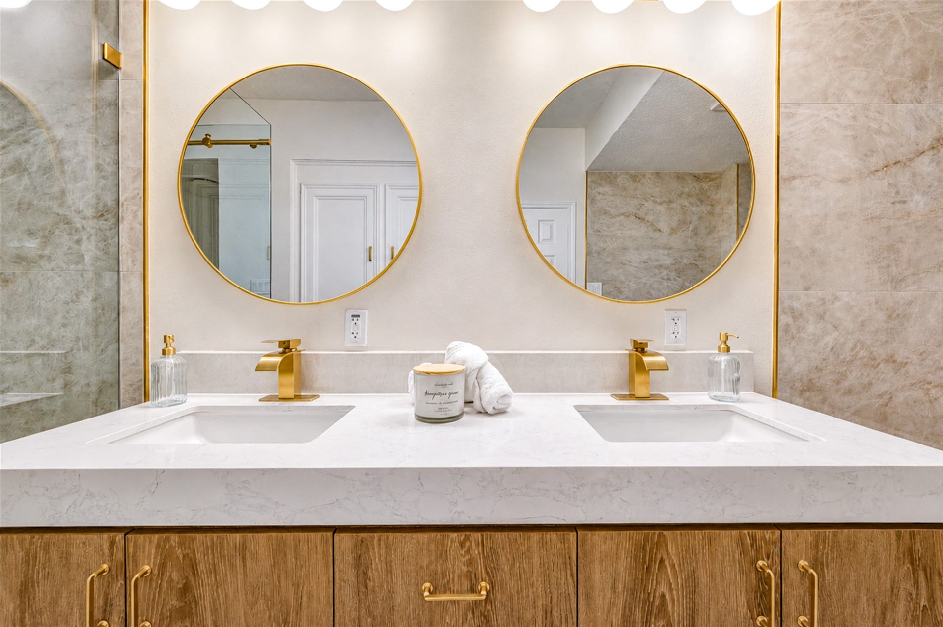 Close-up of the primary ensuites double-sink vanity showcases beautiful finishes, generous counter space, abundant storage and stylish round mirrorscreating a polished, functional space that makes busy mornings and evening routines feel effortless.