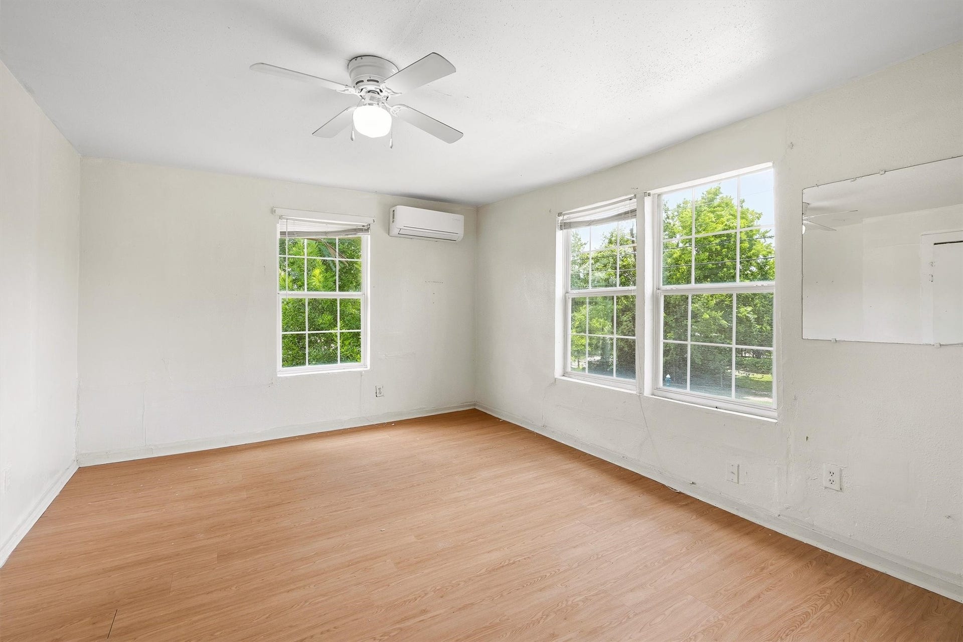 4233 Dupont Street, Houston, TX 77021 This inviting bedroom features laminate flooring, a ceiling fan, and windows with privacy blinds, creating a comfortable and relaxing retreat with a bright, polished feel.