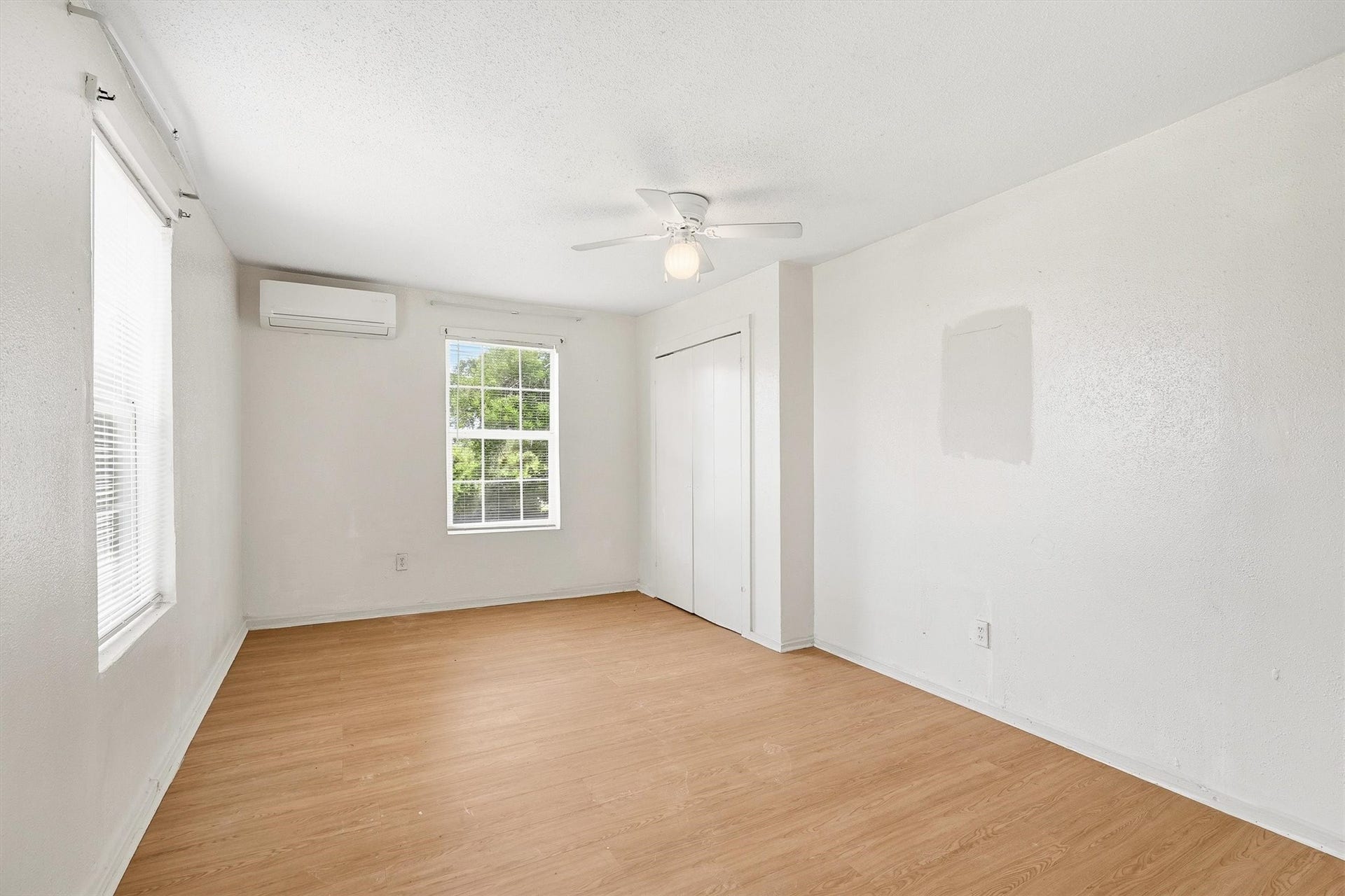 4233 Dupont Street, Houston, TX 77021 The second bedroom offers a comfortable and inviting retreat with laminate flooring, a ceiling fan, and windows with privacy blinds, blending style, comfort, and functionality.